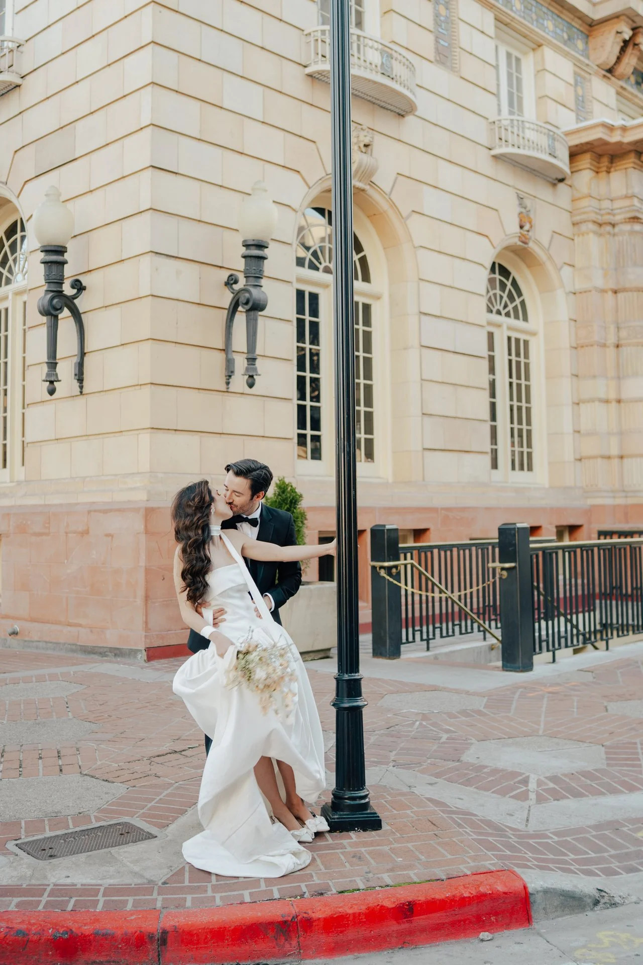 Bride and Groom in classic elegant wedding attire surrounded by beautiful stonework architecture during a downtown formals photoshoot - Poise and Ivy Imagery