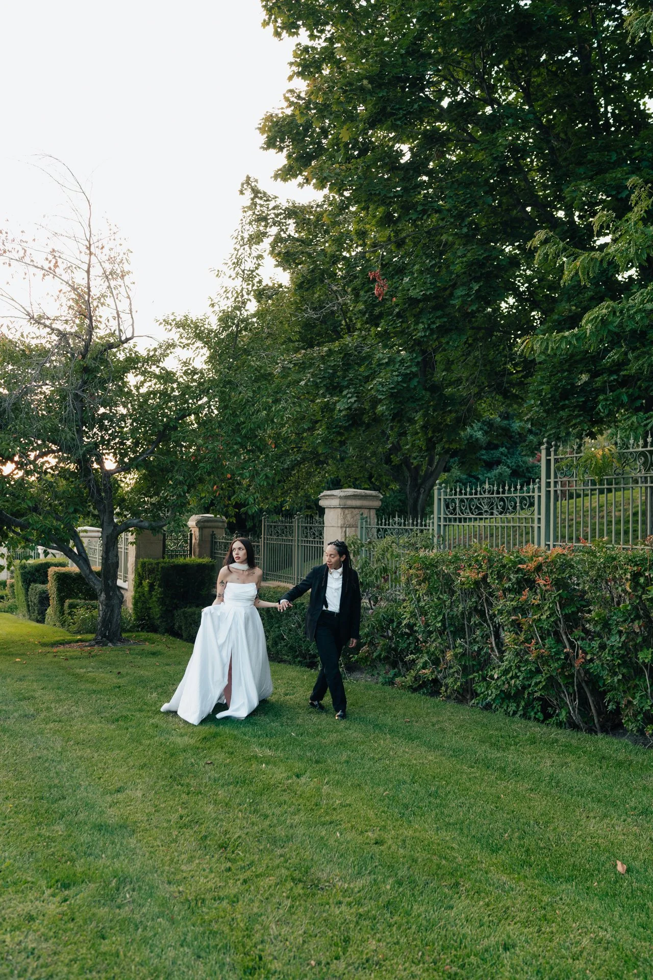 Two brides embrace in front of an ornamental museum of art - poise and ivy imagery