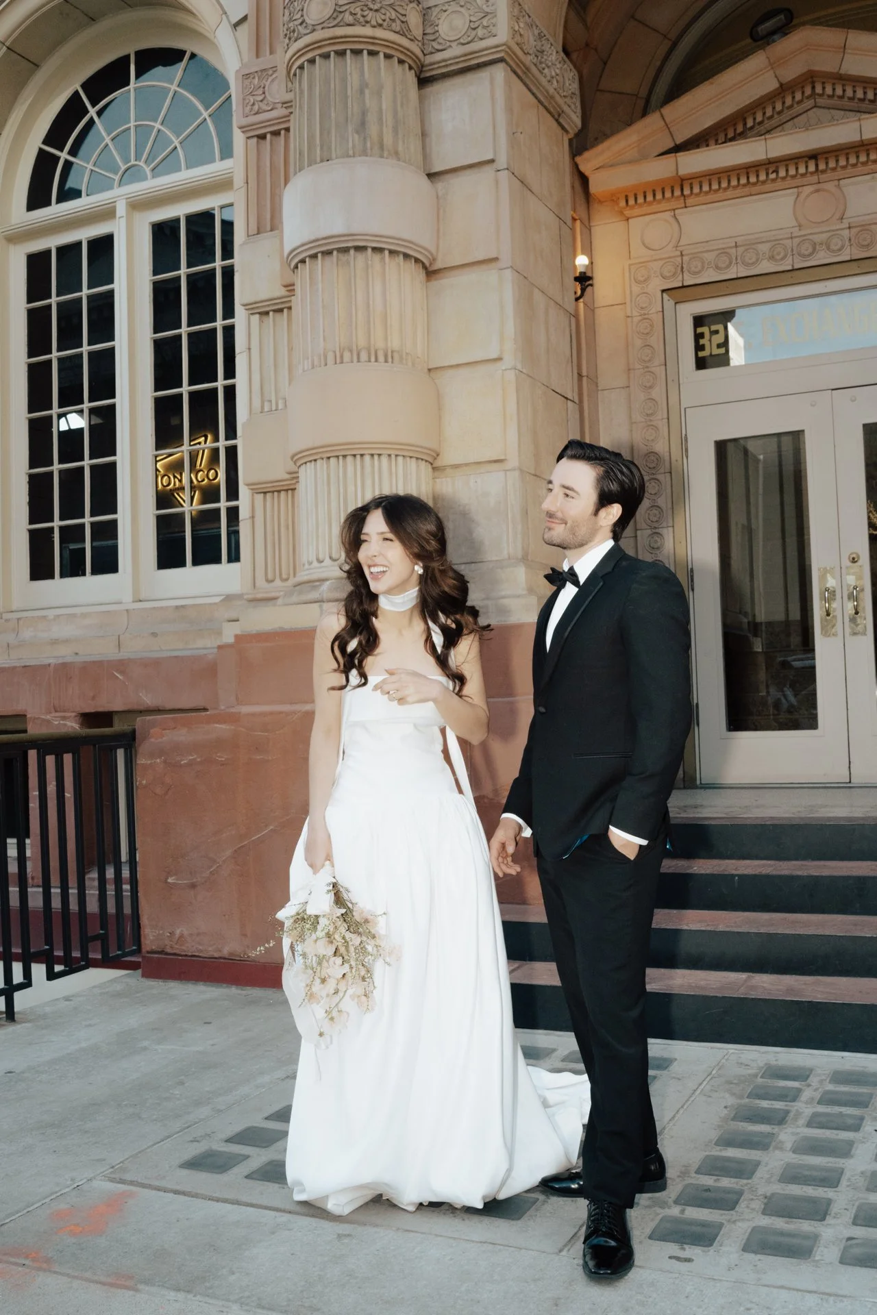 Bride and Groom in classic elegant wedding attire surrounded by beautiful stonework architecture during a downtown formals photoshoot - Poise and Ivy Imagery