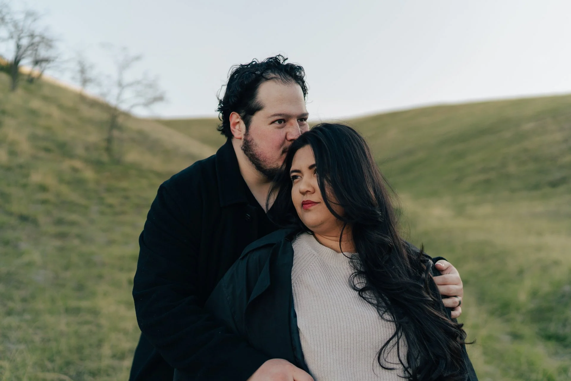 a couple stands together in a softly lit green field together - photographed by poise and ivy imagery