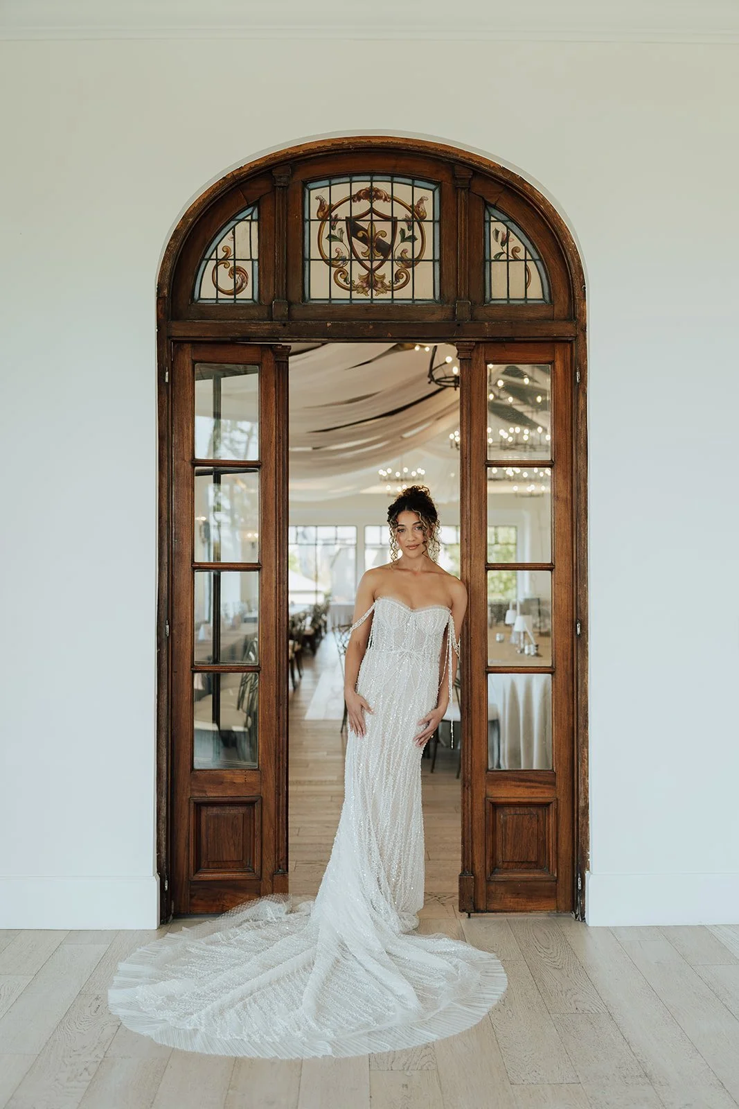 A bride in her wedding gown poses in an ornate arched doorway at Utah's Siempre Wedding Venue, captured by wedding photographer Poise & Ivy Imagery