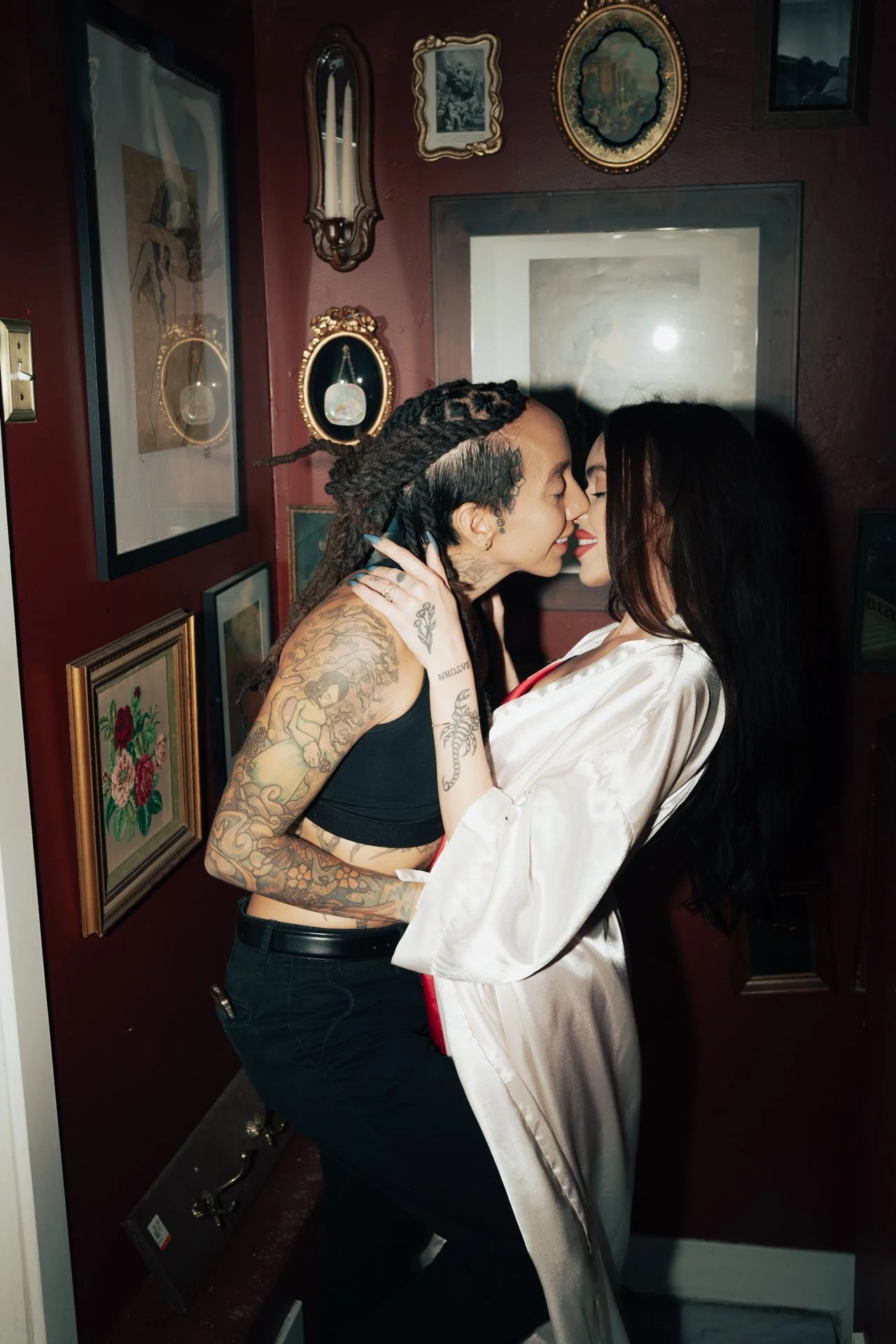 a tattooed couple embrace each other in front of ornate artworks - photographed by Poise and Ivy Imagery