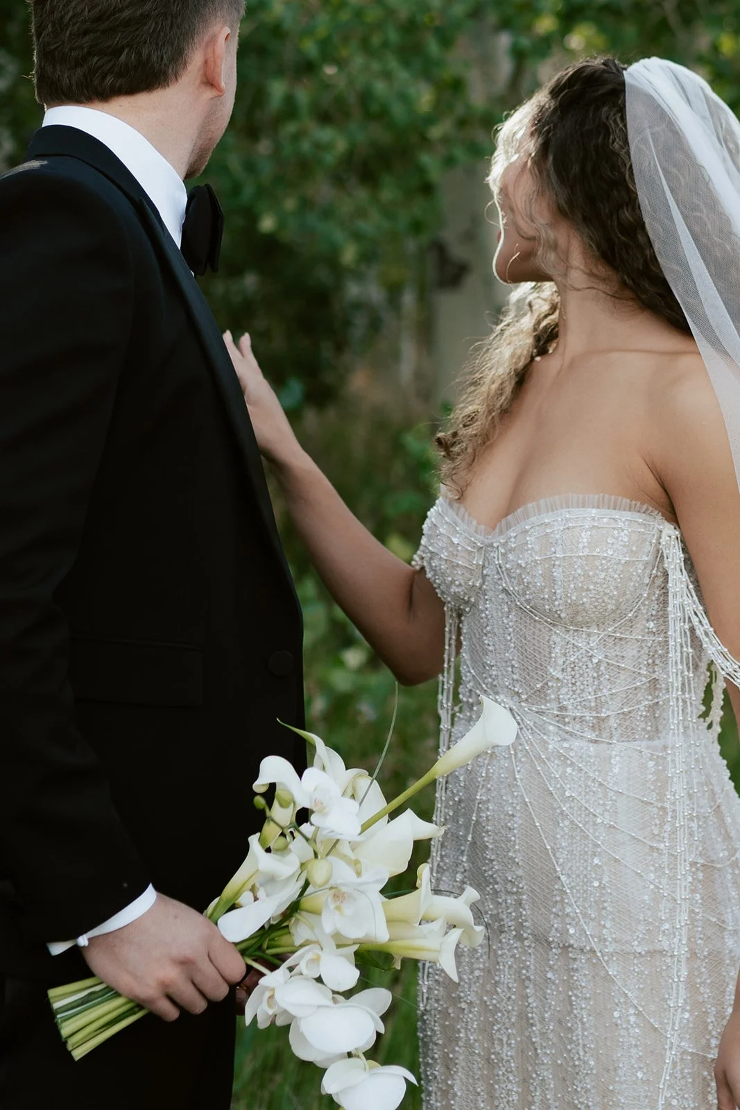 a bride and a groom stand together in a lush aspen grove. the bride wears a beaded wedding gown and the groom wears a tuxedo. Photography by Poise and Ivy Imagery