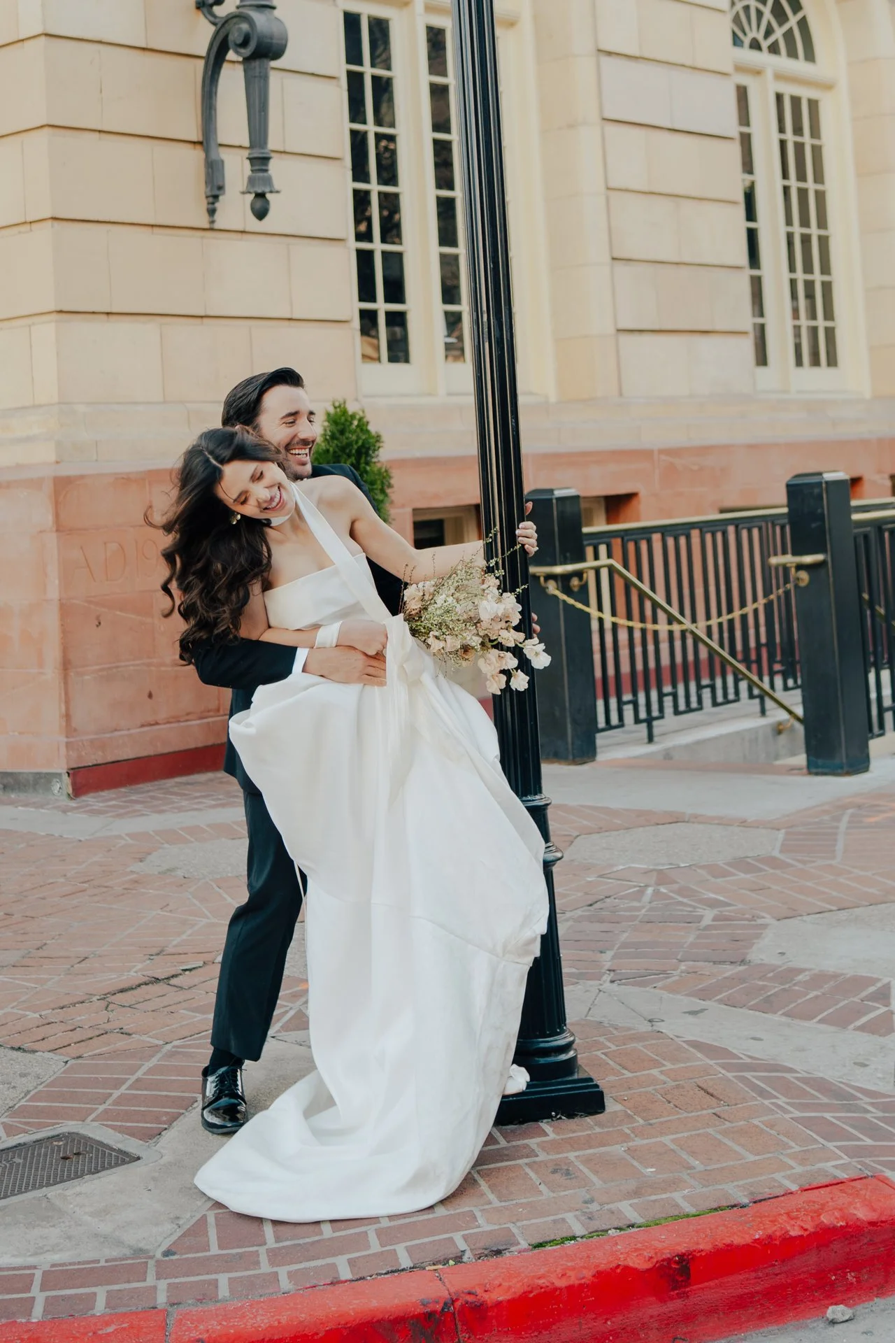 Bride and Groom in classic elegant wedding attire surrounded by beautiful stonework architecture during a downtown formals photoshoot - Poise and Ivy Imagery