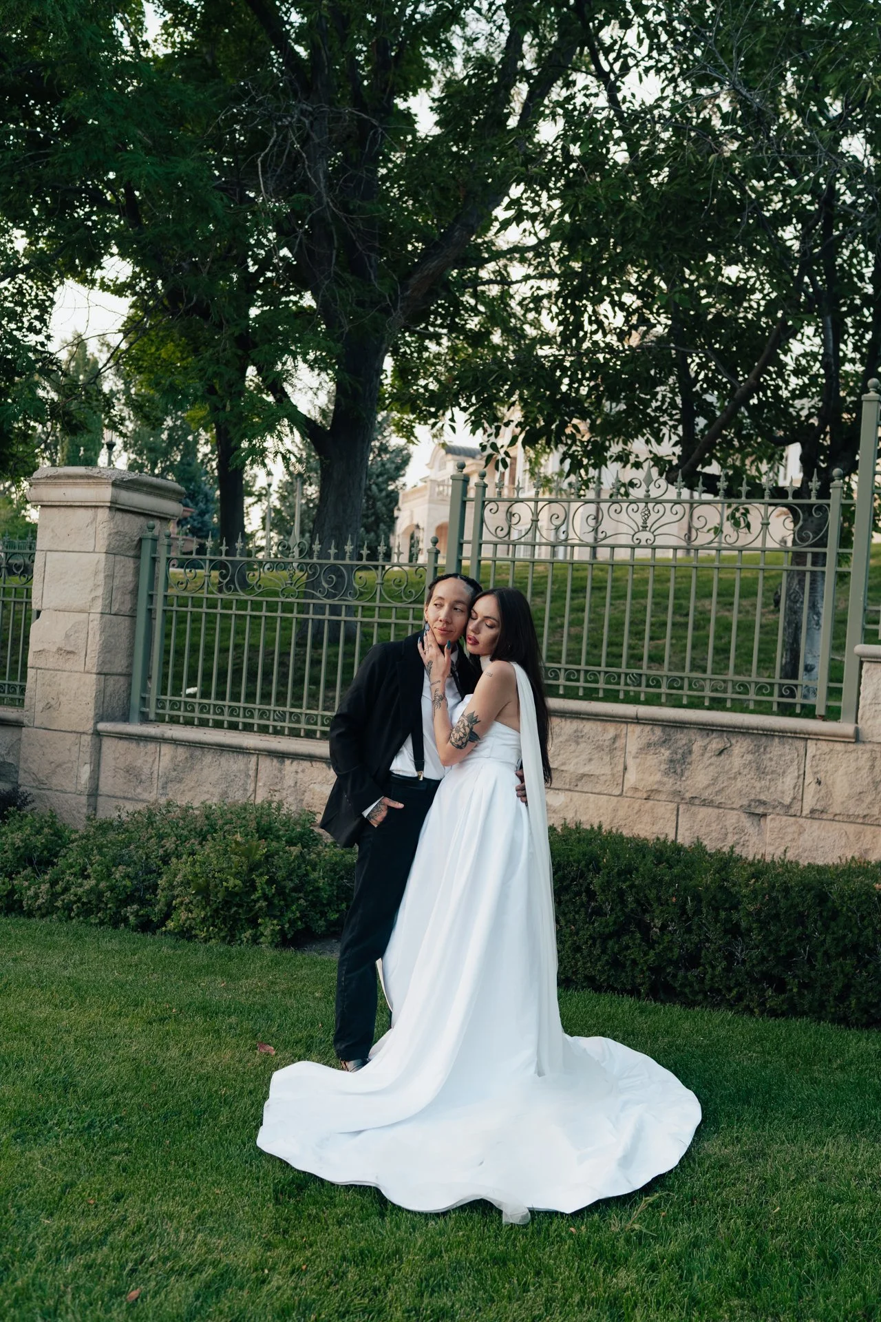 Two brides embrace in front of an ornamental museum of art - poise and ivy imagery