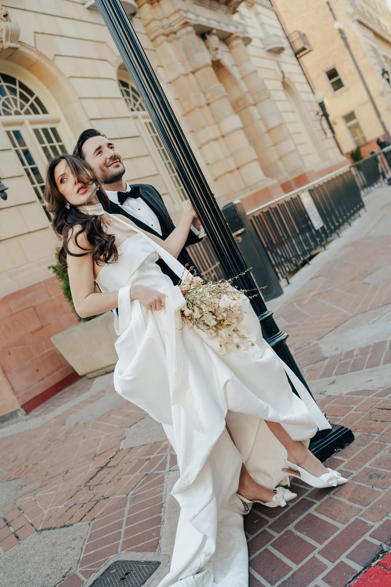 Bride and Groom in classic elegant wedding attire surrounded by beautiful stonework architecture during a downtown formals photoshoot - Poise and Ivy Imagery