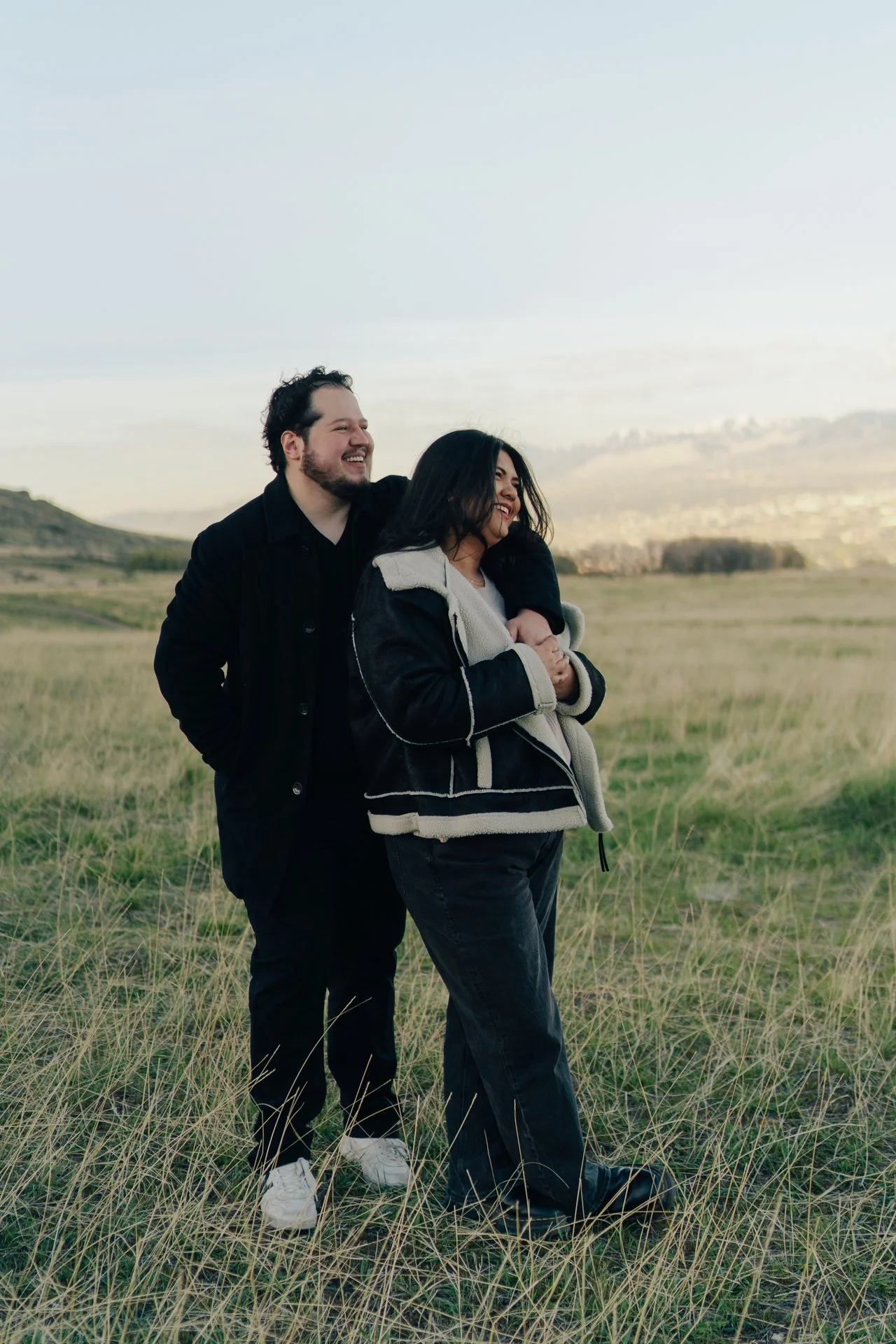 a couple stands together in a softly lit green field together - photographed by poise and ivy imagery