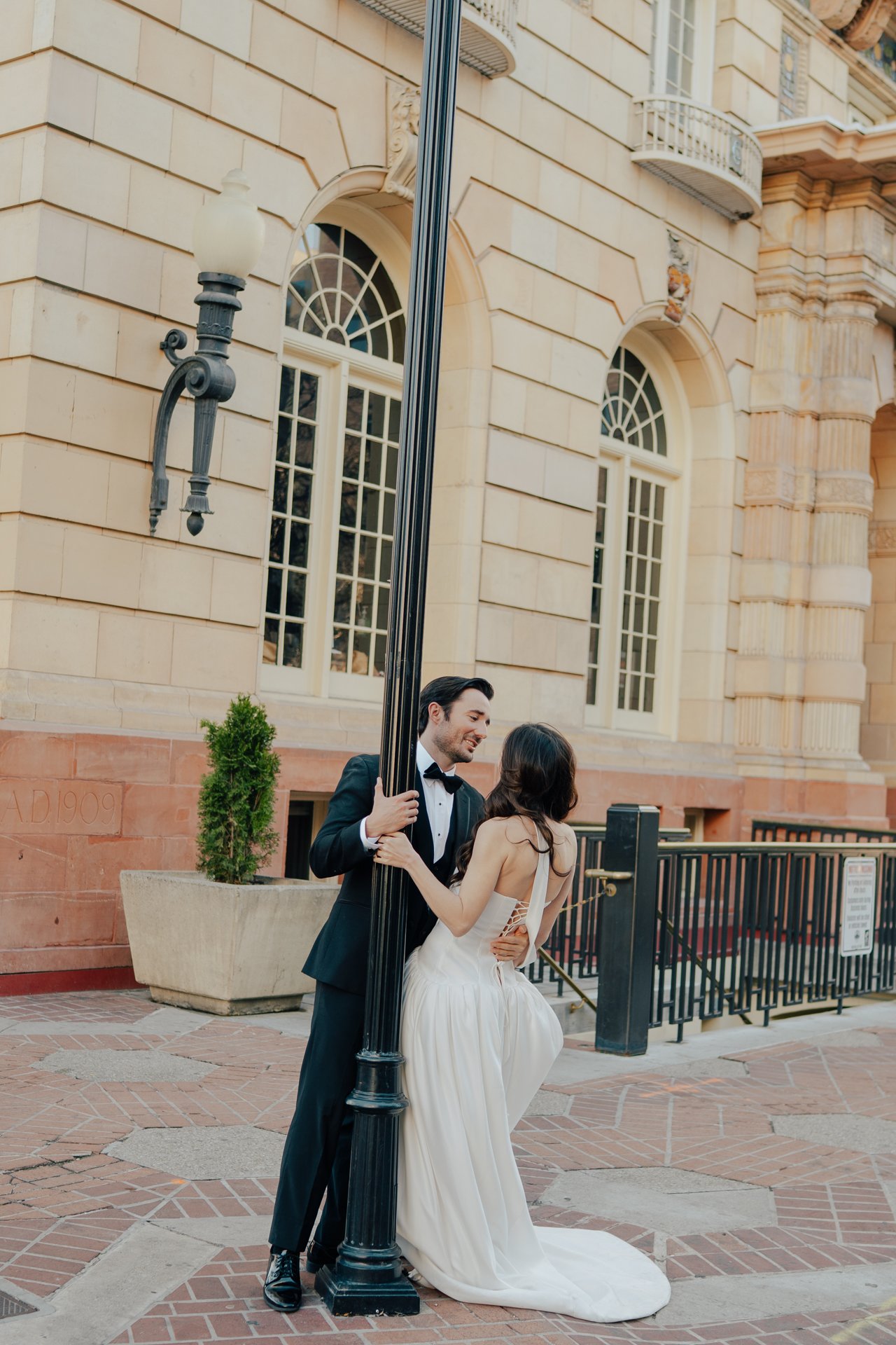 Bride and Groom in classic elegant wedding attire surrounded by beautiful stonework architecture during a downtown formals photoshoot - Poise and Ivy Imagery