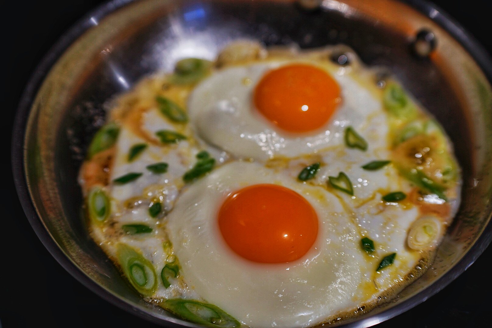 Two farm-fresh sunny side up eggs cooked with mirin, rice vinegar, sesame oil, and scallions. Cooked, shot, and styled by Ellen Avigliano.