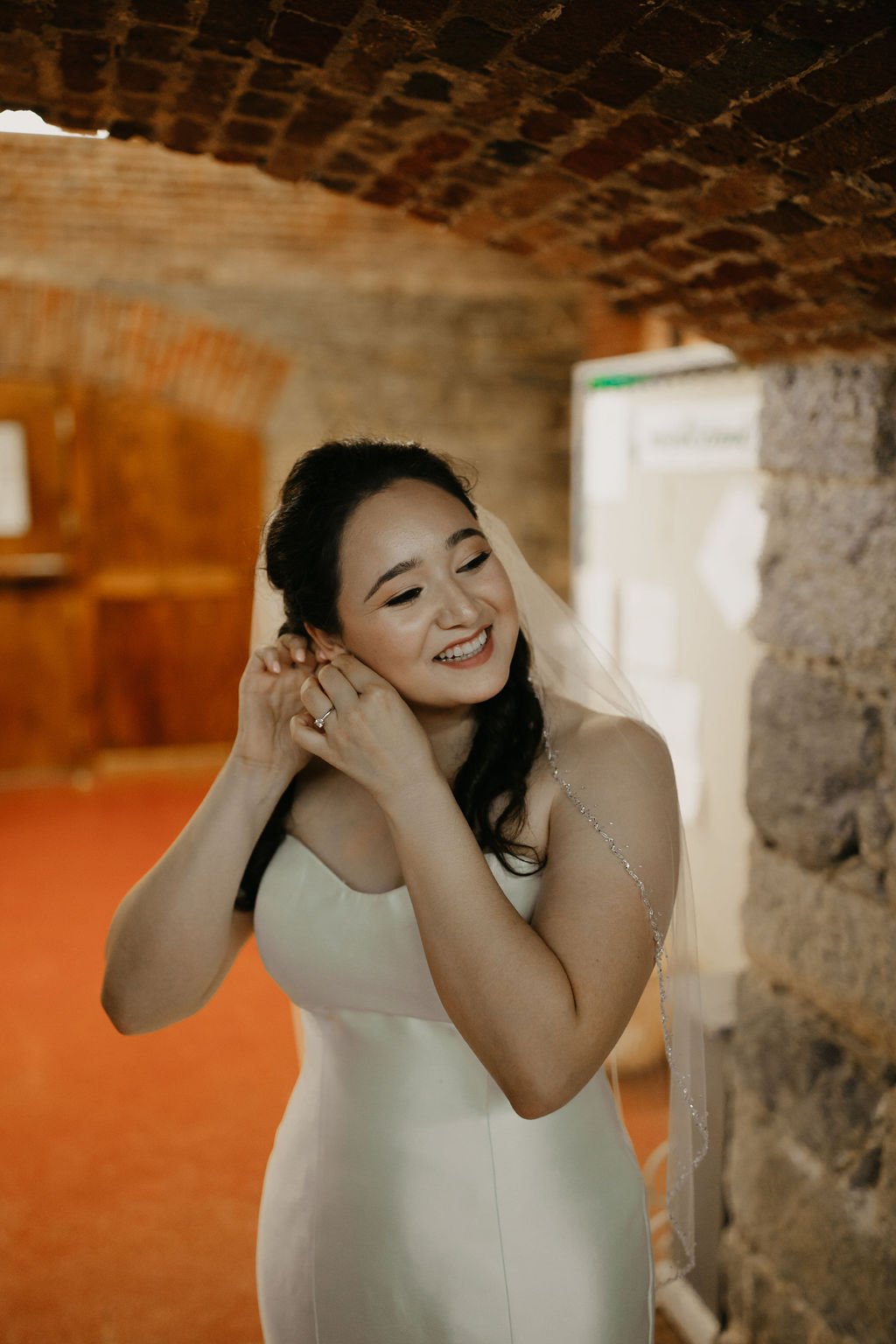 bride in all white with glowing skin, adjusting her earring