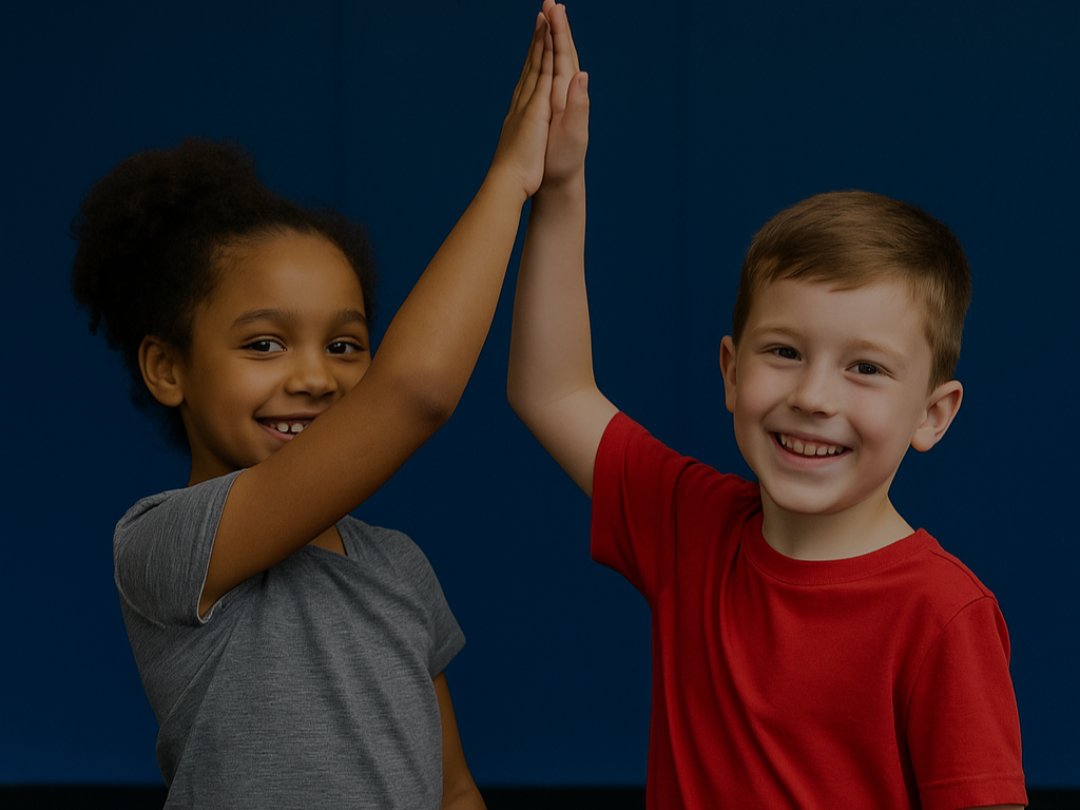 Two smiling kids giving a high five in front of a blue background, representing CrossFit Kids program at CrossFit 1864 East London near Canary Wharf.