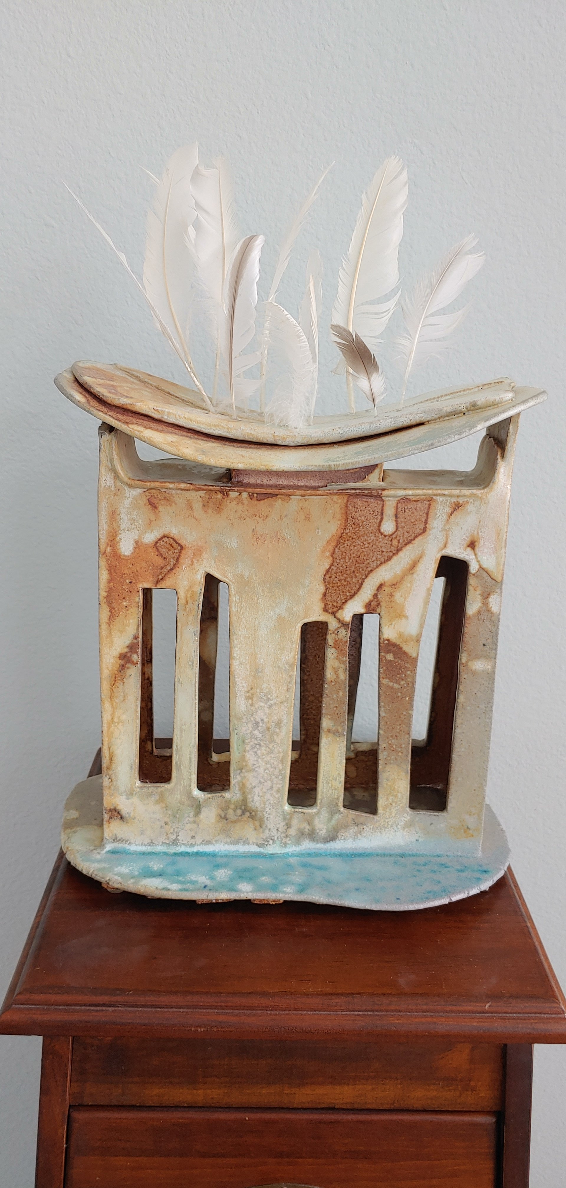2nd Place Winner; Nancy McElroy; Free To Fly; Clay /Soda Fired and Feathers; This sculpture was fired in a soda-fire kiln.  Sodium chloride deposits give it this rich color.  The cage is empty...and the bird is free.; $900