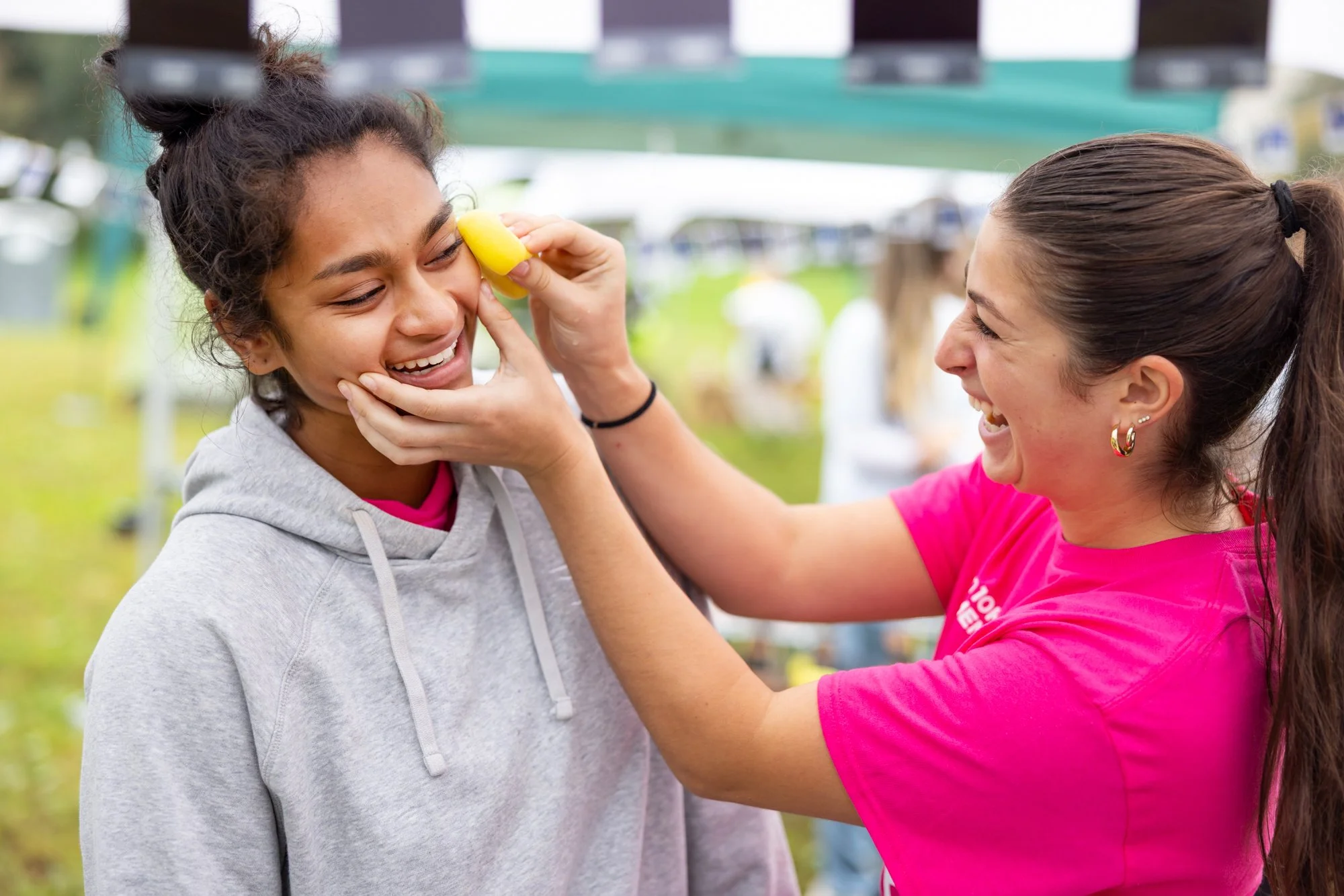 Two friends laughing while putting makeup on