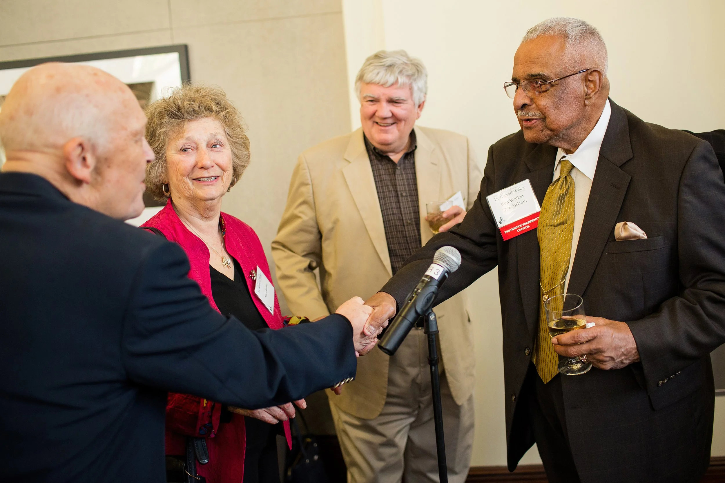Honoree at event reaching out to shake hands with friend
