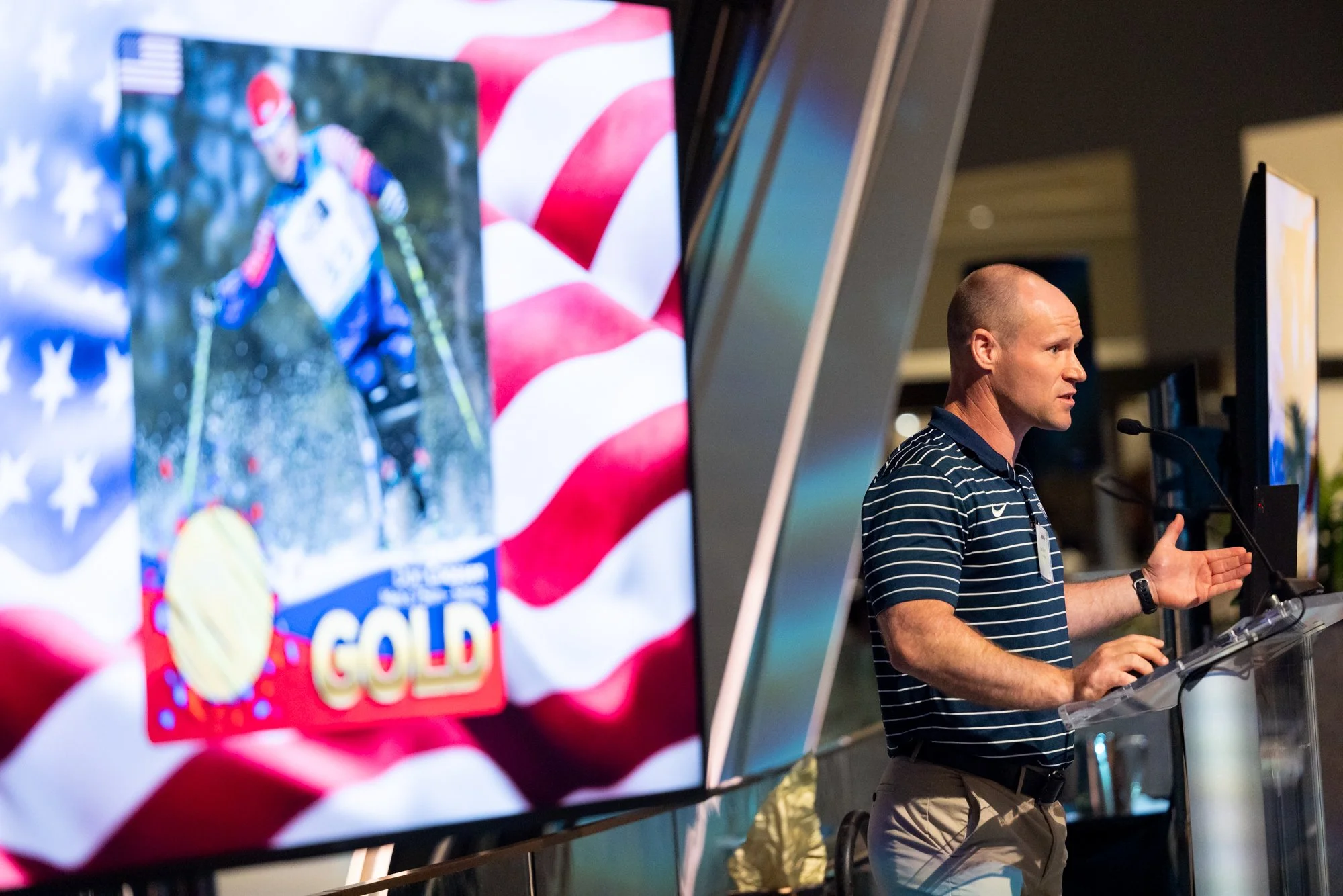 Man speaking at podium with screen