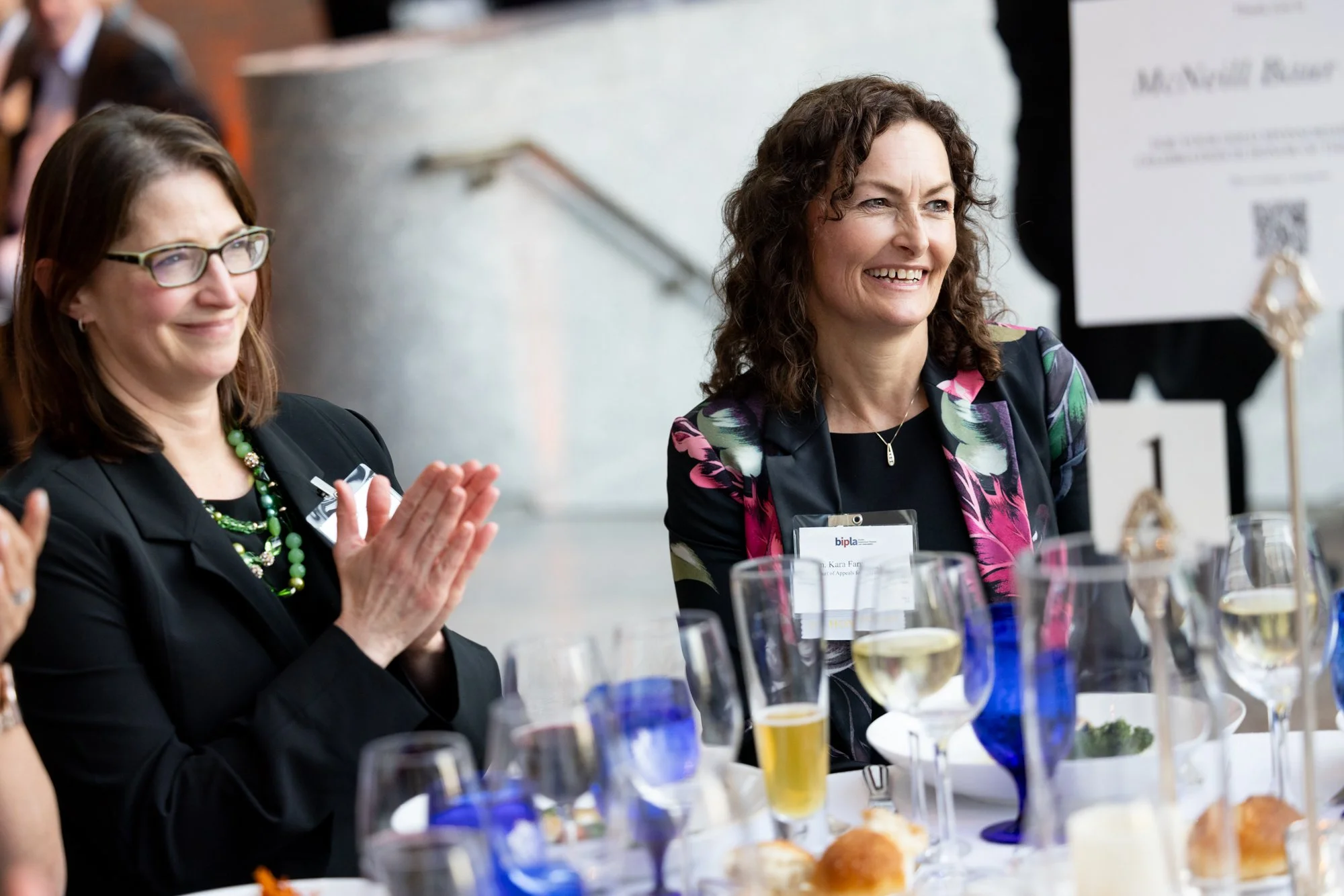 Two women seated at table and one is clapping