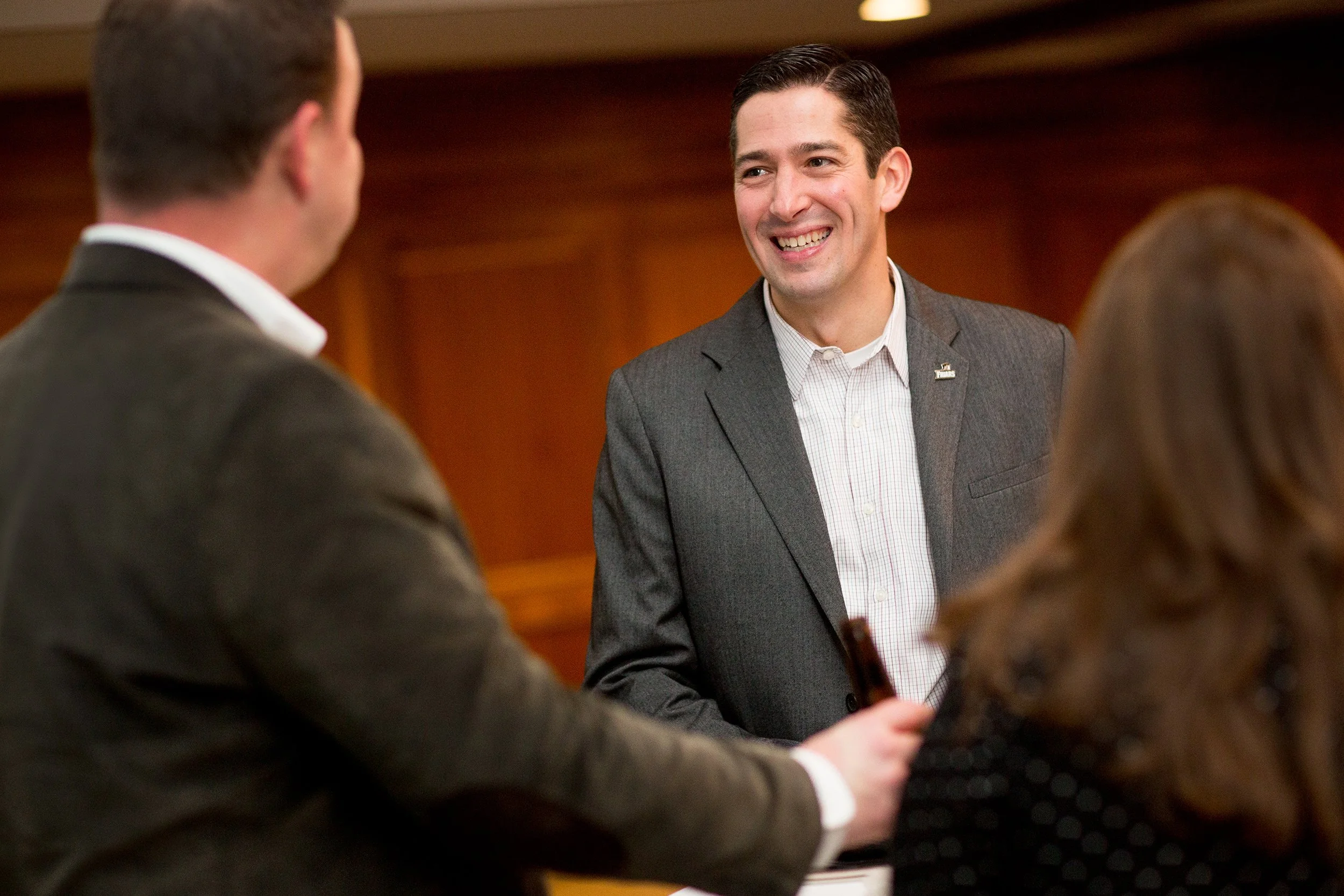 Man smiling while talking to someone at event