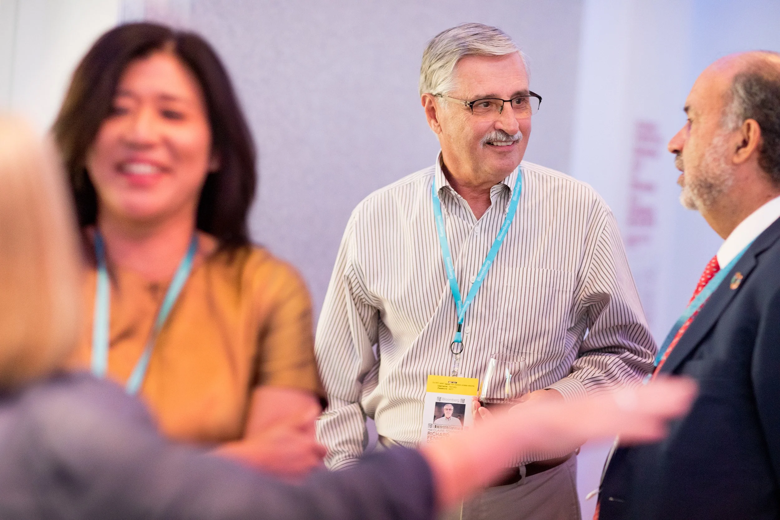 Networking event showing woman in foreground and two people speaking in background