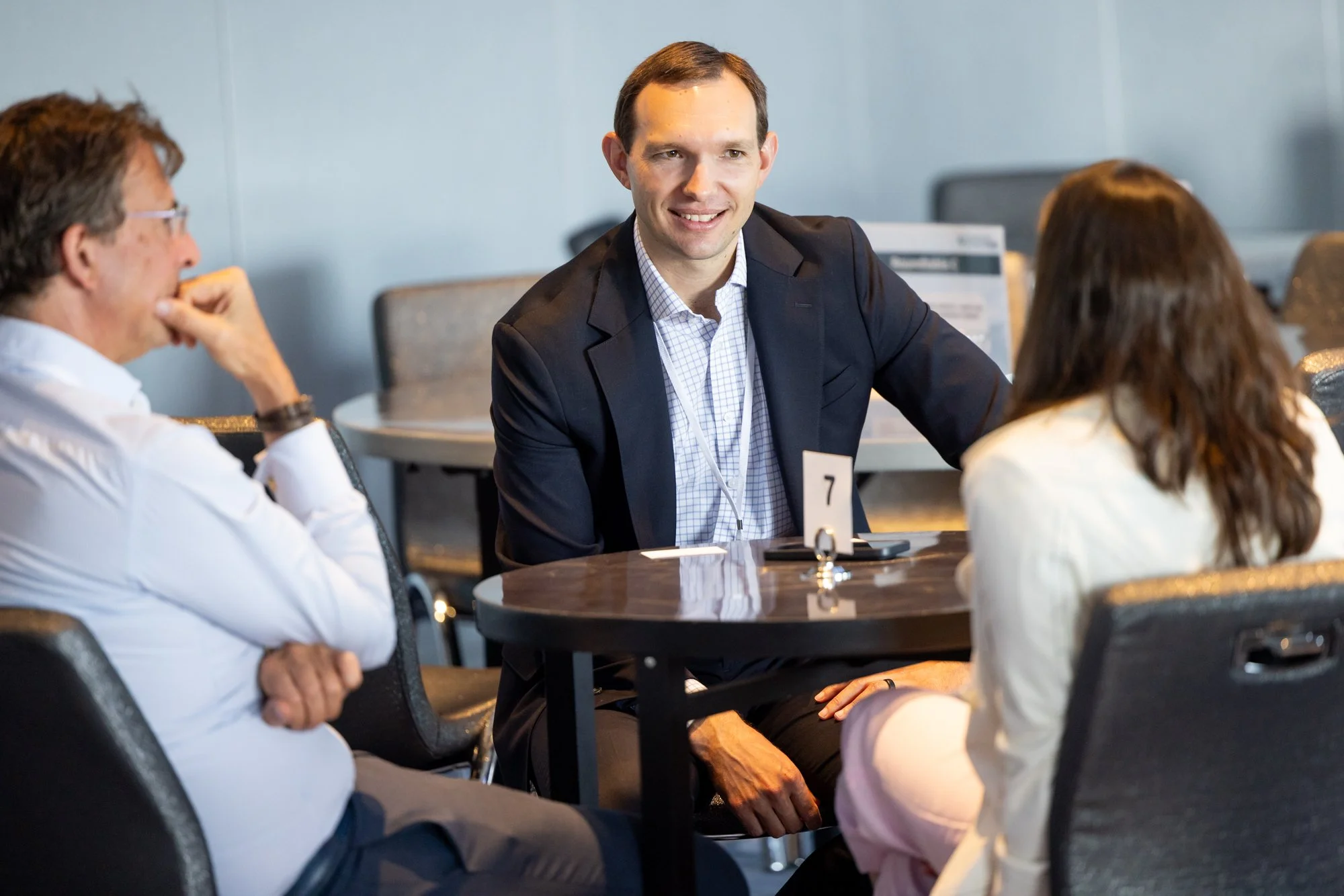 Three people speaking at table during conference