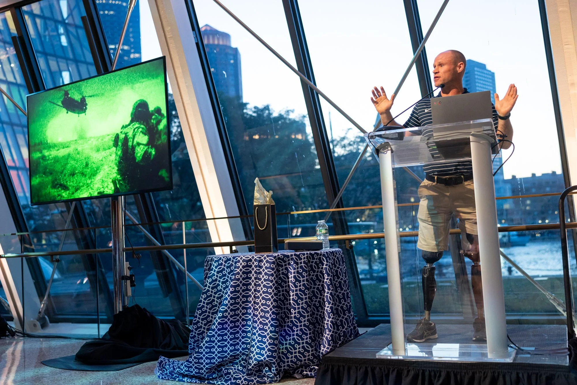 Man standing at podium speaking with windows in background
