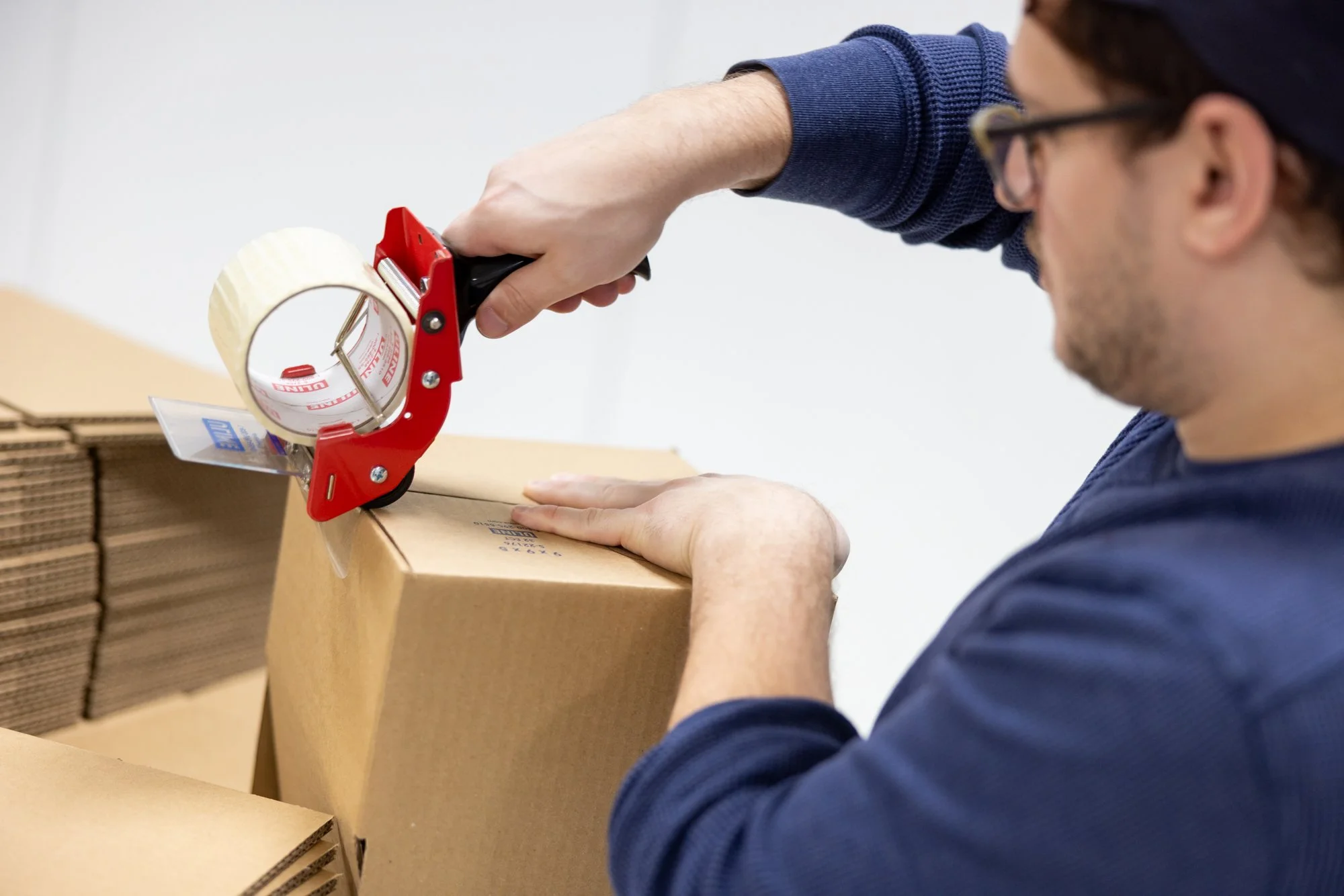 Man using a tape dispenser closing a box
