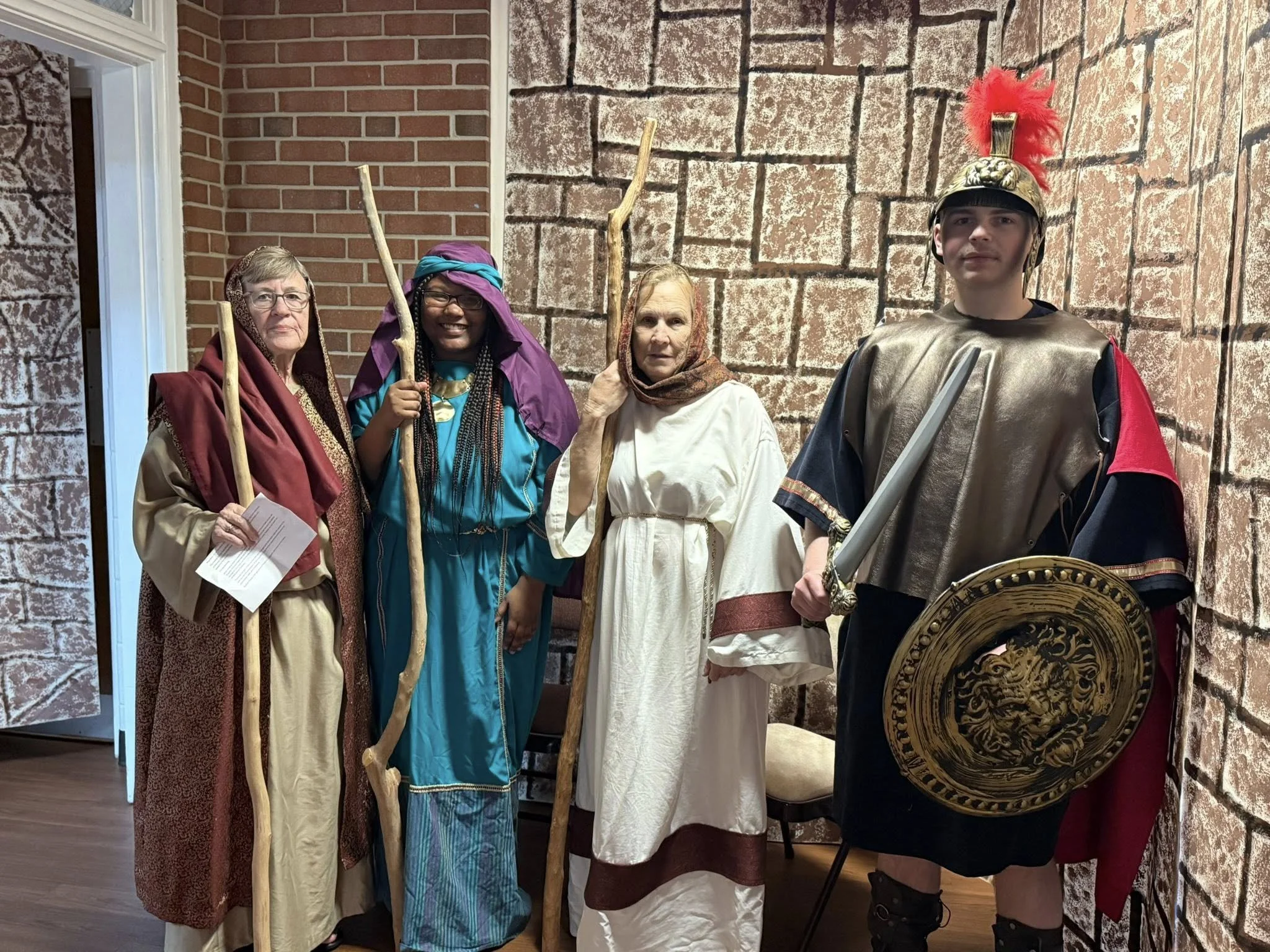 Four Journey to Easter volunteers pose in costume in front of painted backgrops.