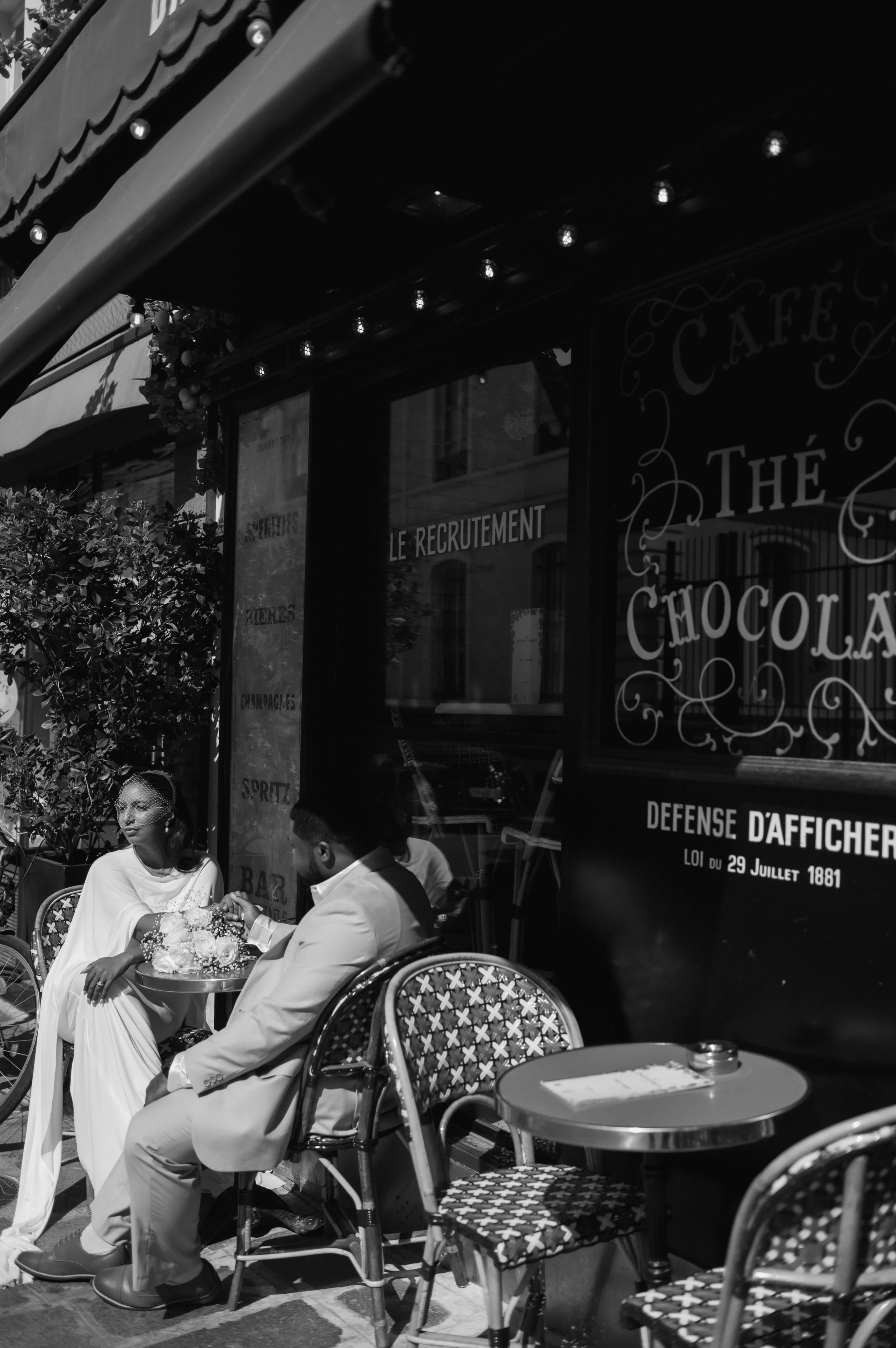 Brid and groom sitting outside Parisian café with flowers after Paris elopement