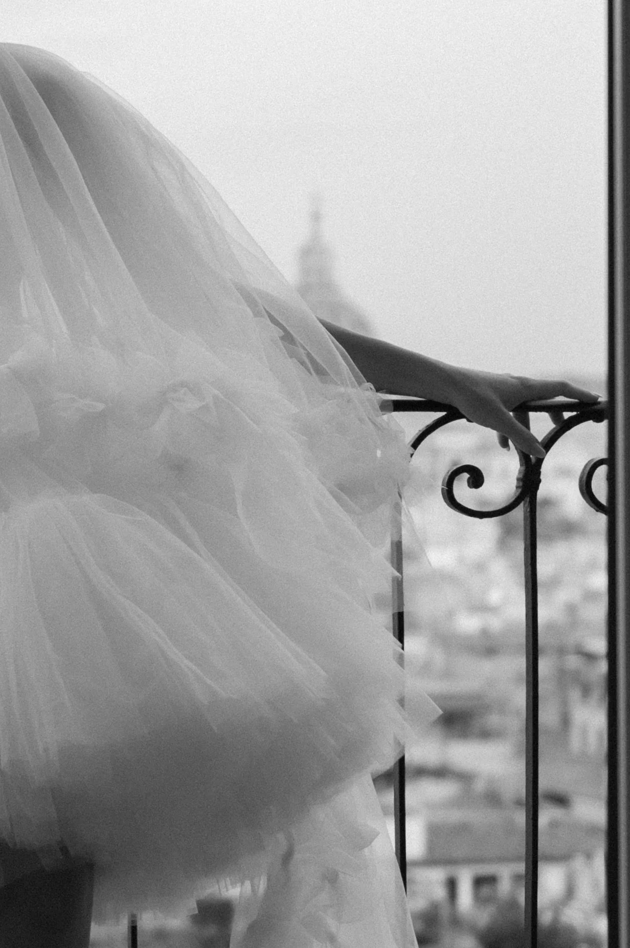 Bride on balcony overlooking city in Rome in black and white