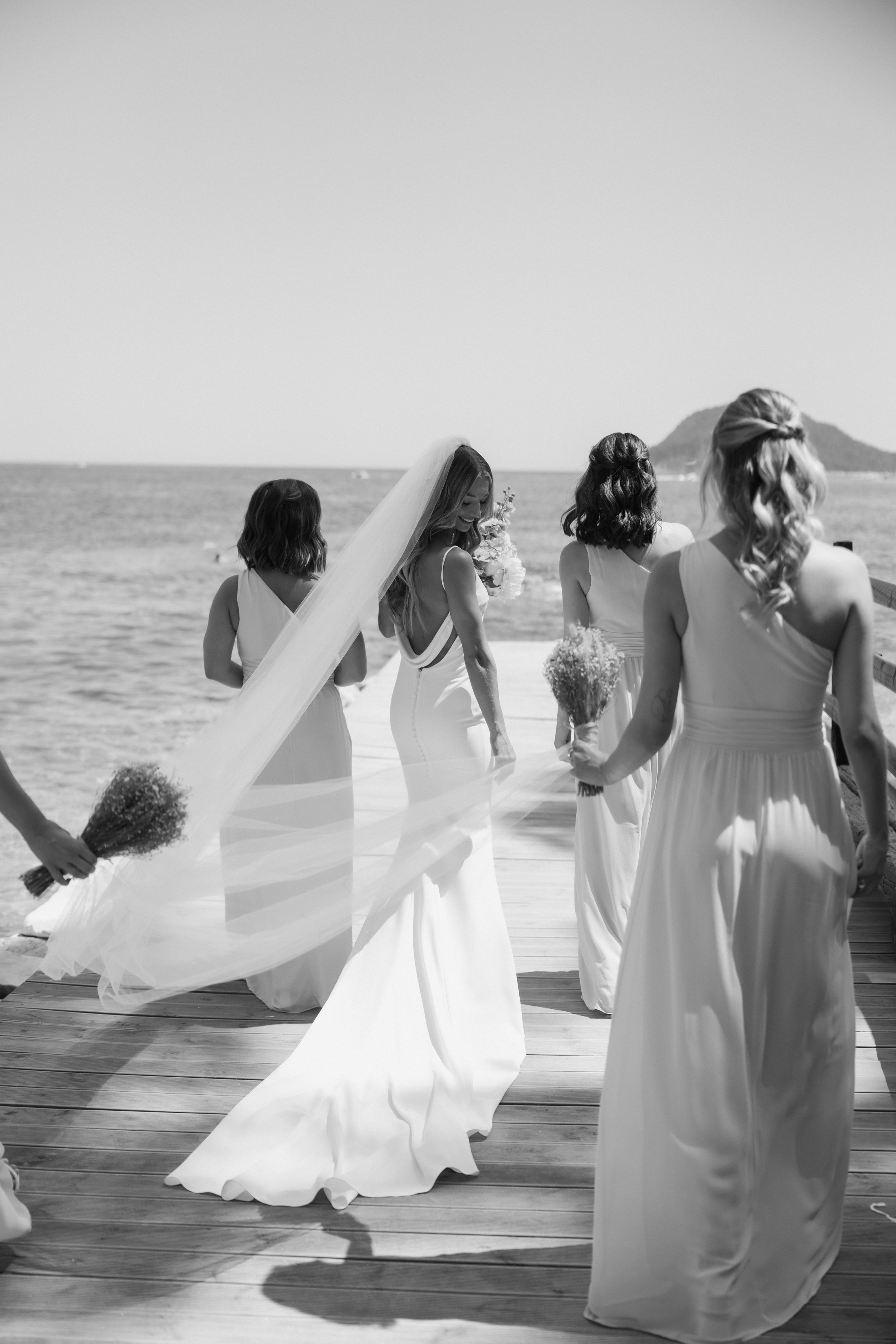 Bridal party  by the ocean with bouquets after wedding ceremony on Cameo island in Greece