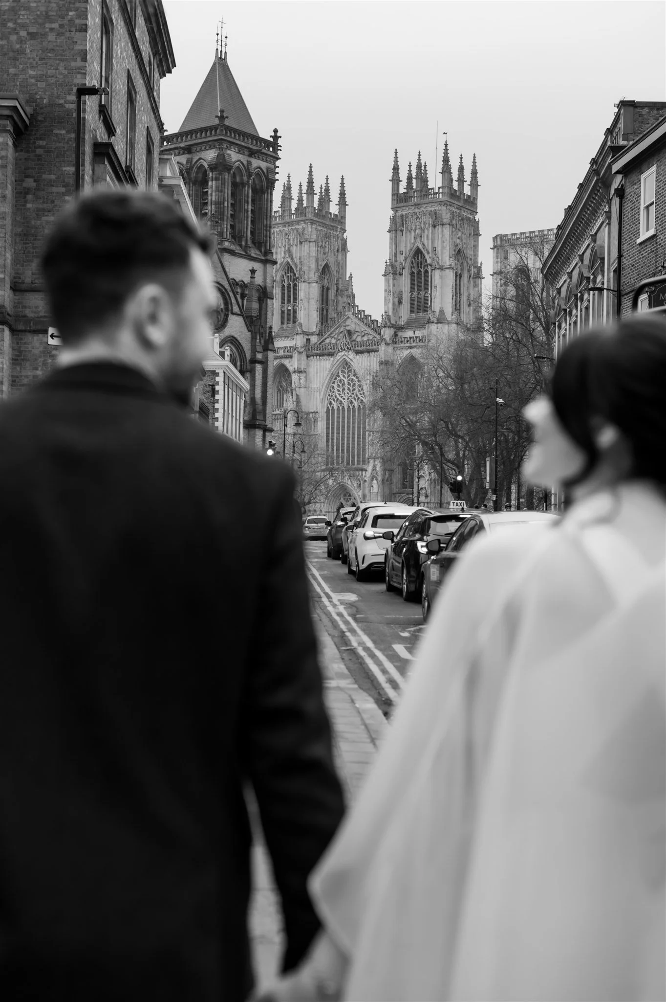Couple walking on city street with York Minster in the background 