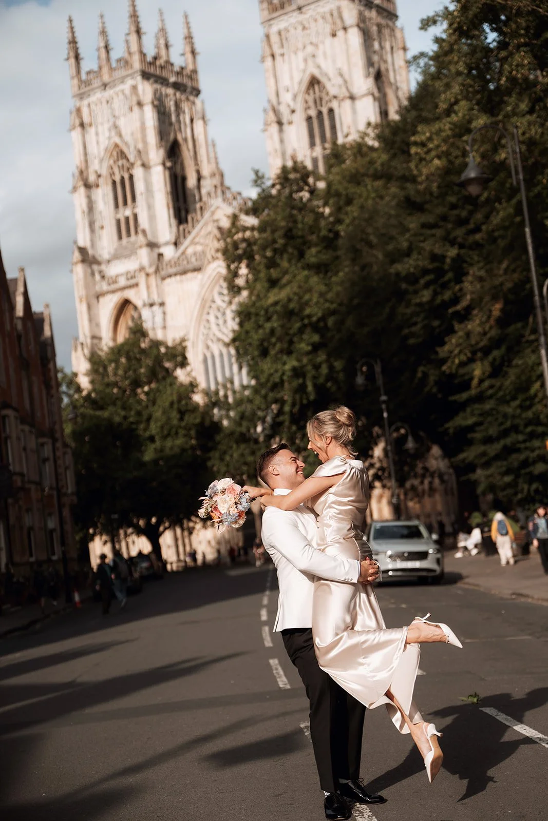 Groom lifting bride on city street outside York Minster 