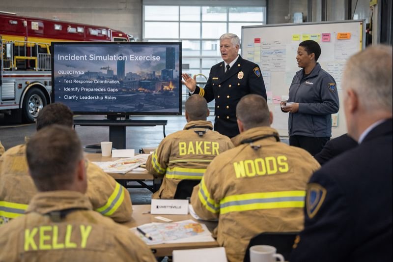 Fire and public safety personnel participating in a structured training and preparedness exercise, reviewing an incident simulation and evaluation objectives during a facilitated session.