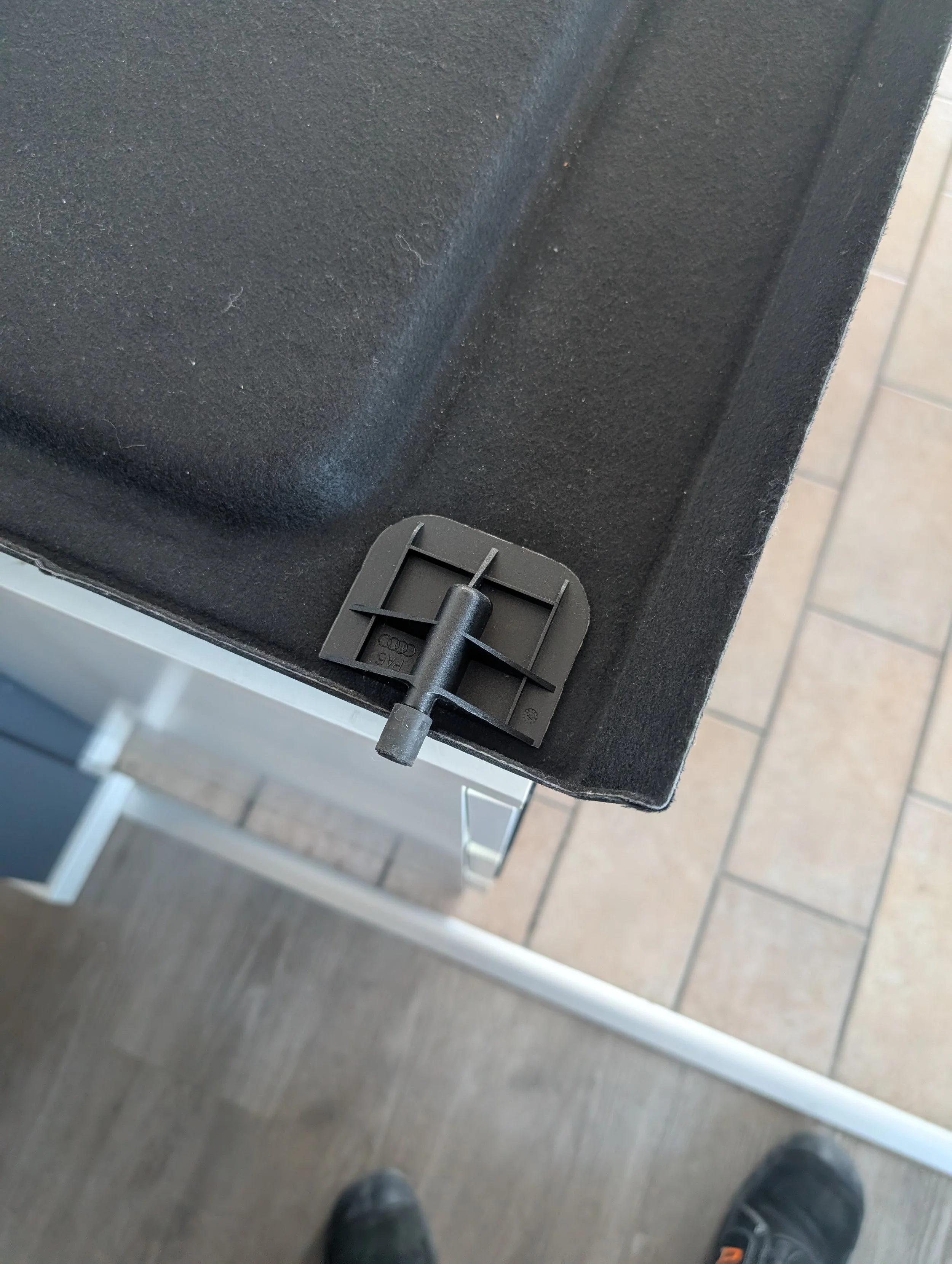 Originalhållare på undersidan av en Audi Q2-hatthylla, med ribbad plastkropp och utstickande tapp