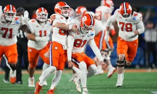 Football players in orange and white uniforms celebrate on the field.
