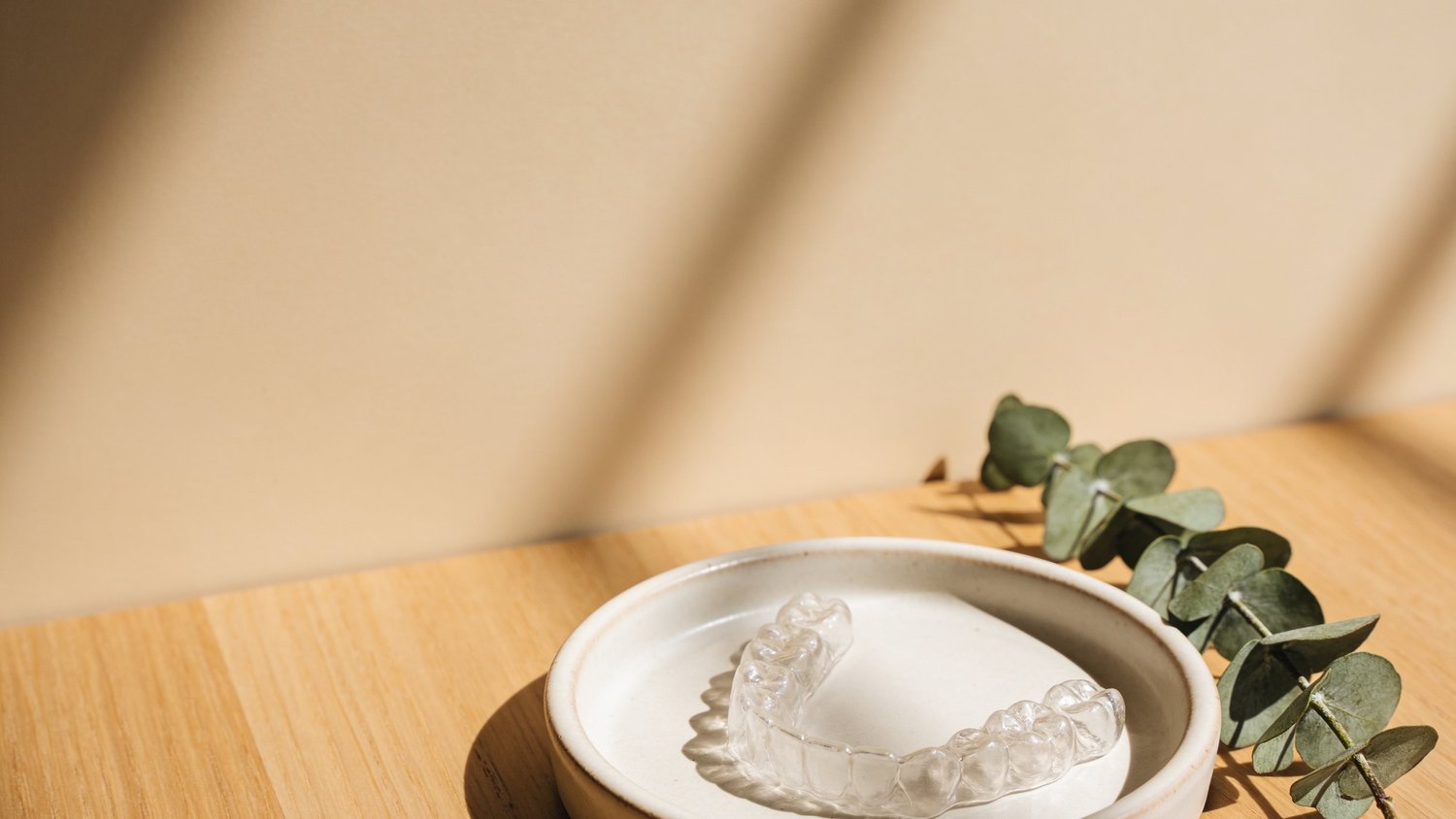 A clear Invisalign aligner on a ceramic dish