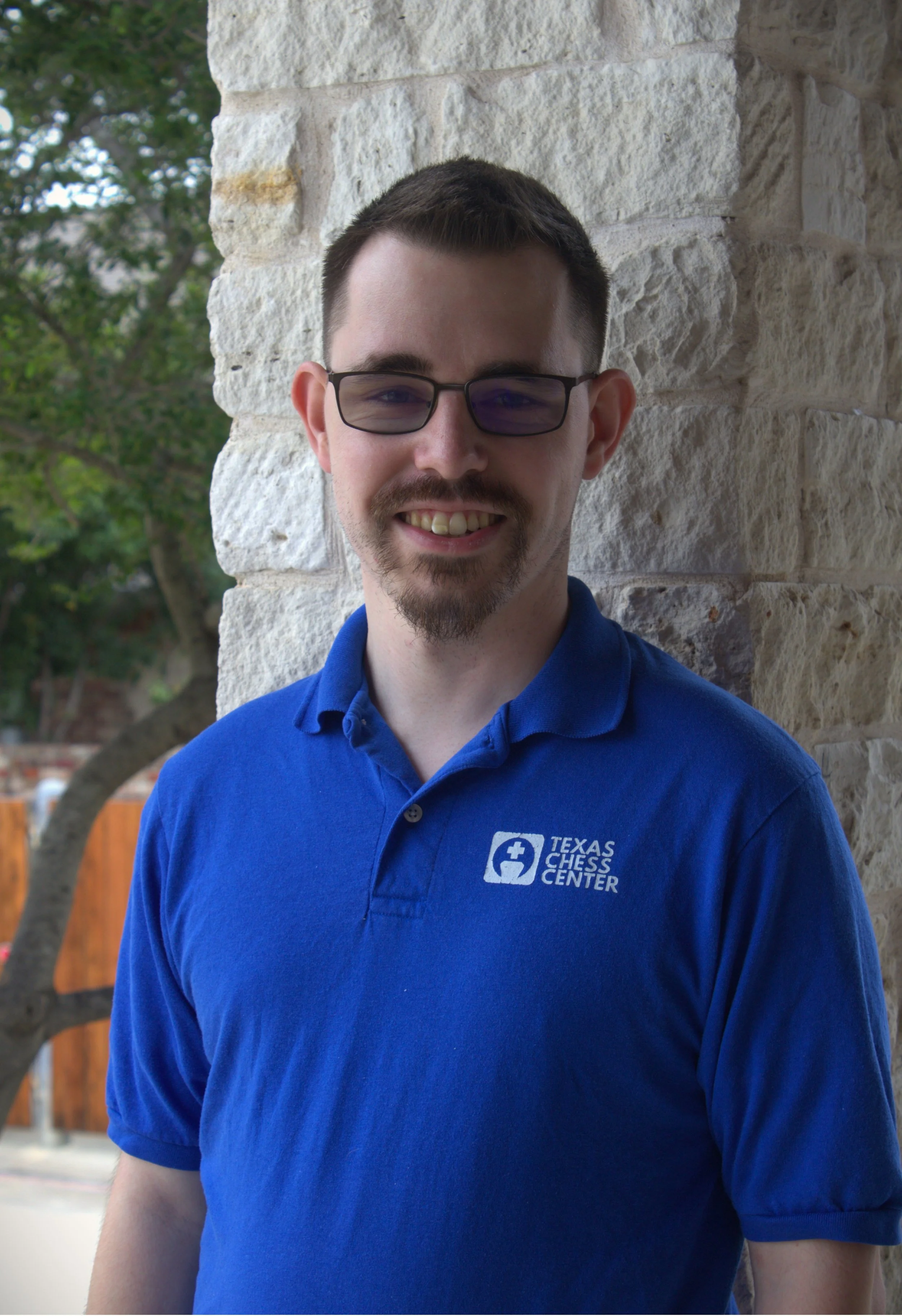 Christian Baca, TCC Frisco Location Supervisor and chess coach, at a chess board contemplating a position.