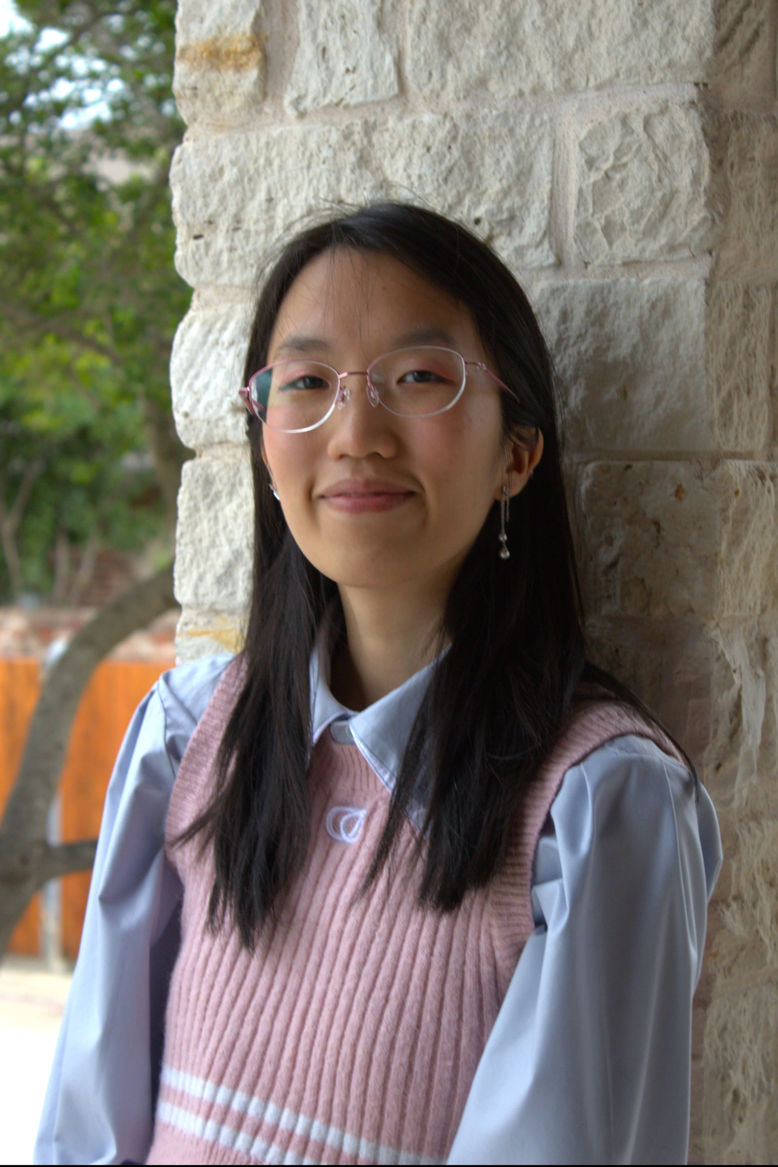 Grace Vu, marketing manager and chess coach, smiling against a background of foliage.