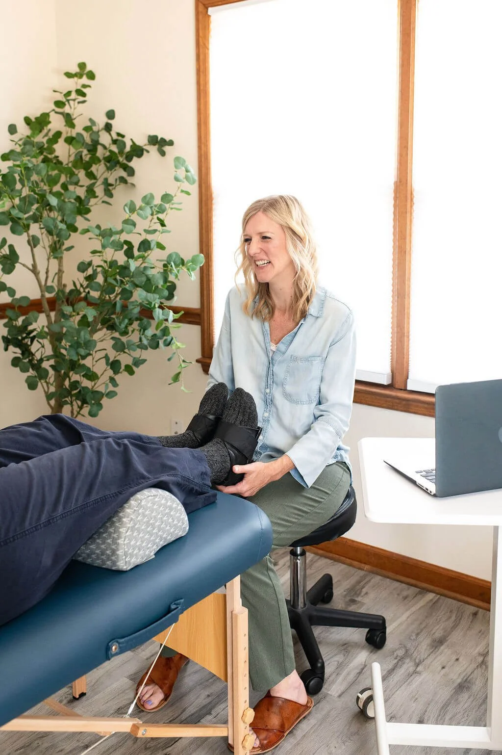 Caitlin Samson smiles at patient while holding the magnet treatment shoes during a biomagnetism therapy session