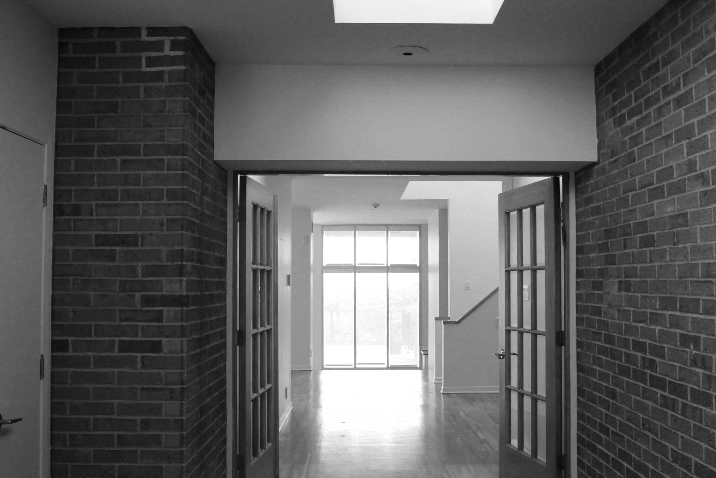 View through open French doors into a brightly lit interior room with large window