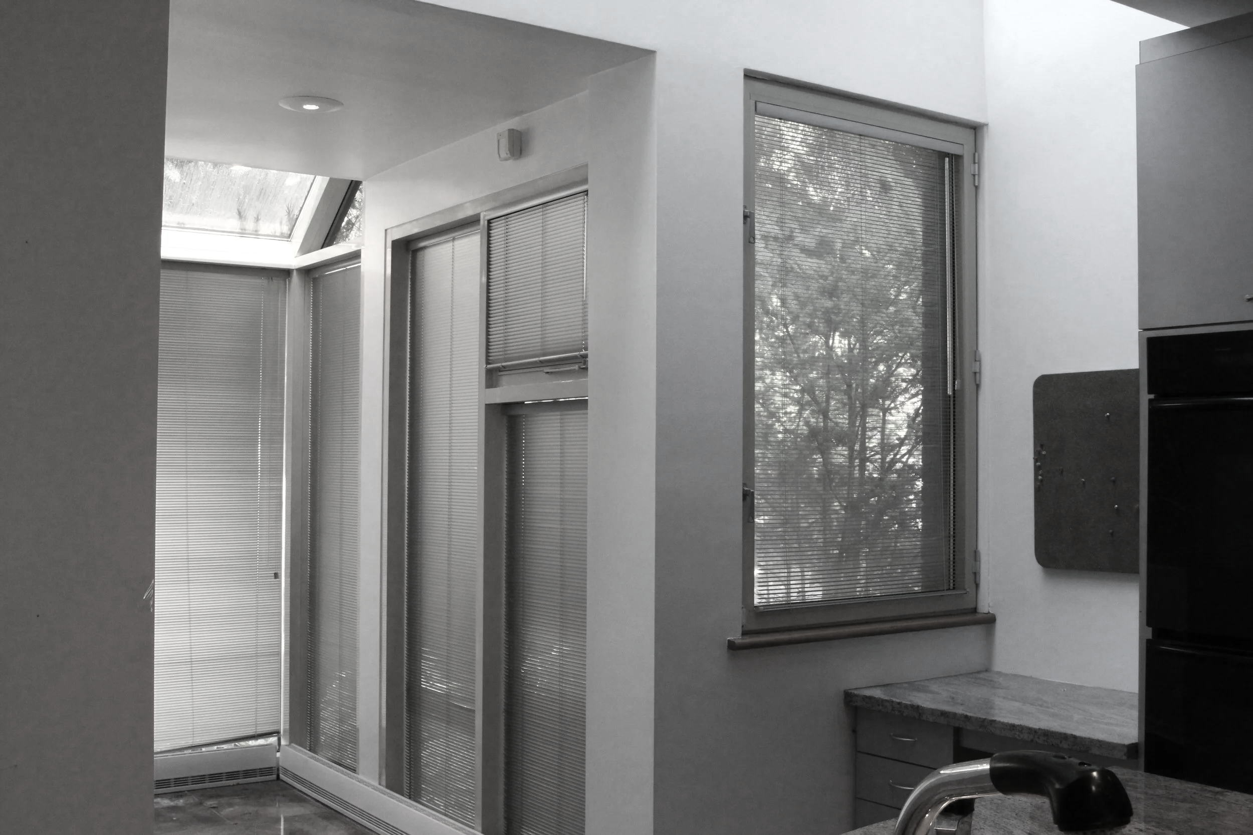 Kitchen with large windows and blinds, including a skylight in the ceiling, and a granite countertop.