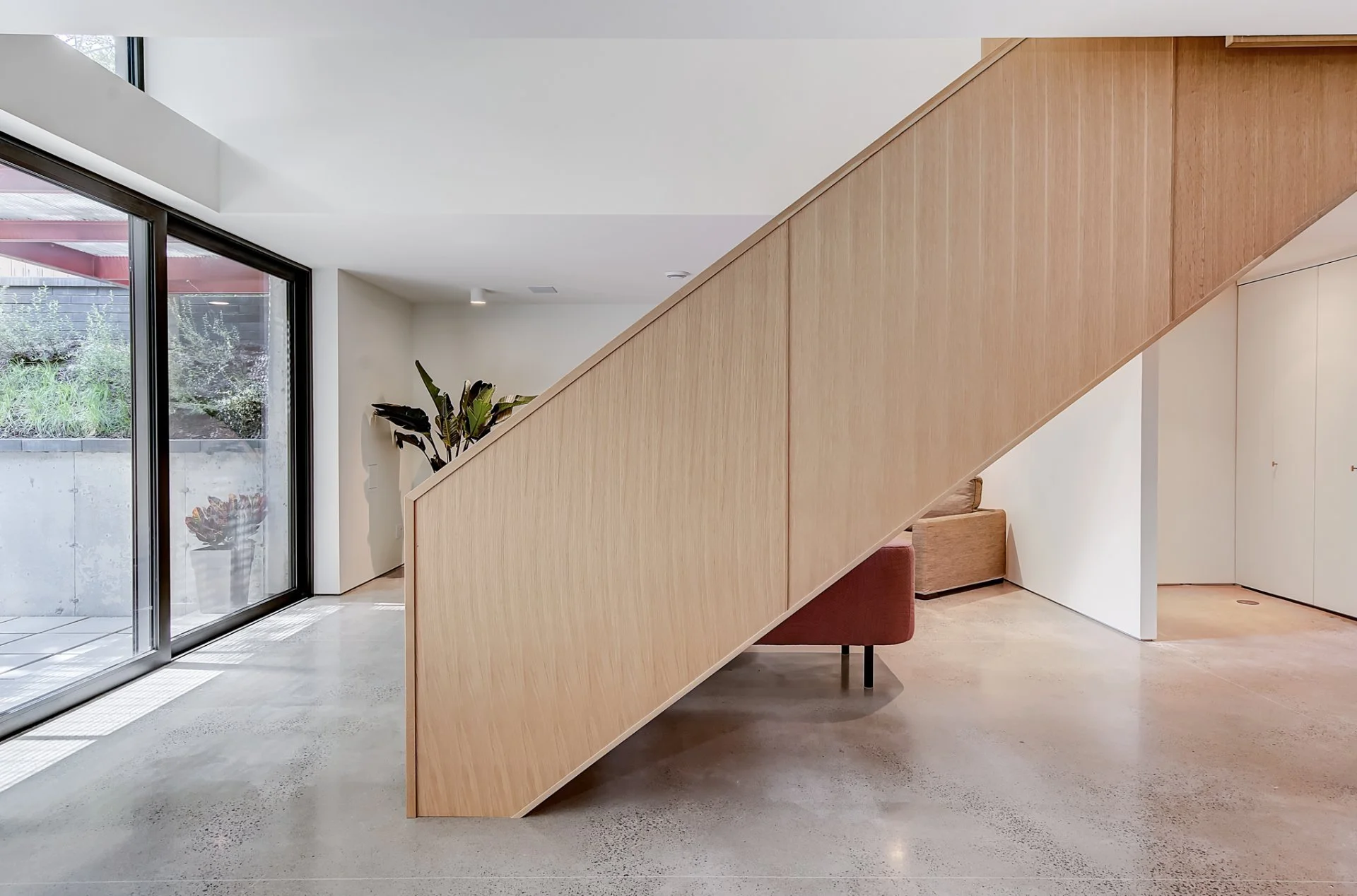 Modern interior with oak staircase, large glass sliding doors leading to excavated english garden
