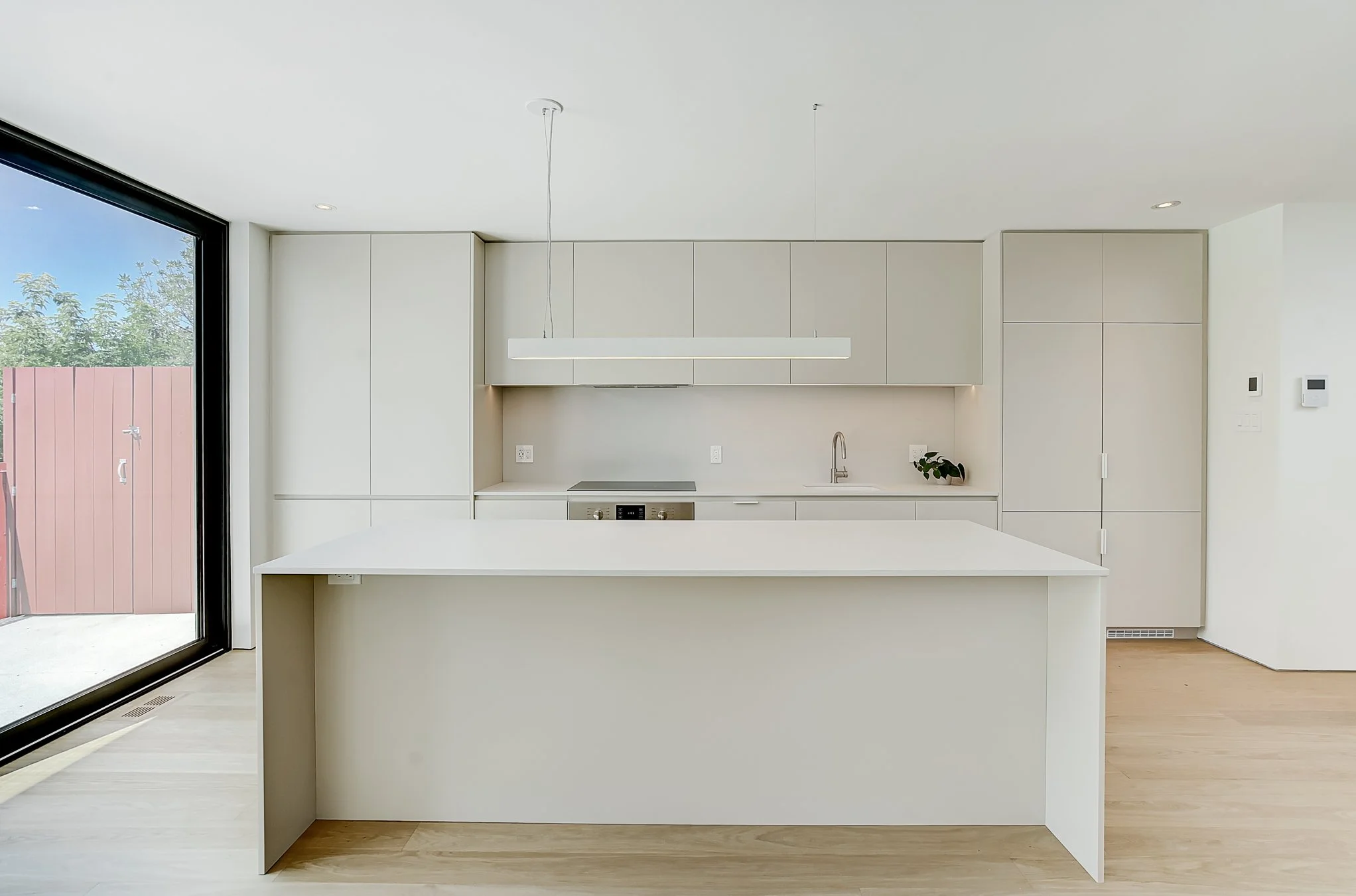 Modern minimalist kitchen with white cabinets, a white island, and a large sliding glass door