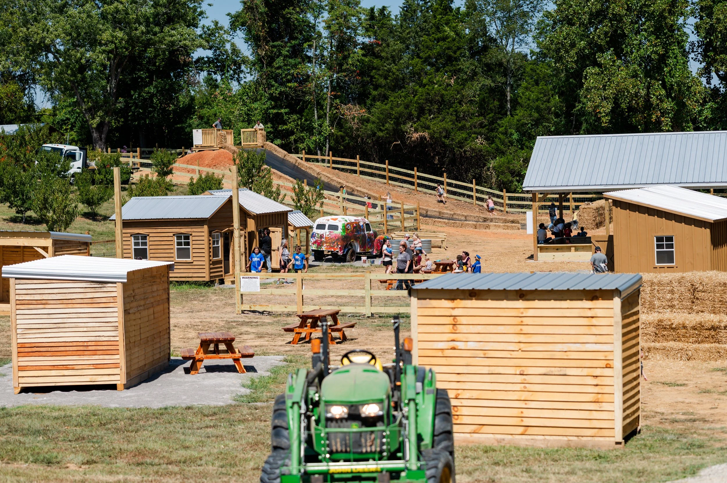 A young woman with curly hair, wearing glasses, smiling in an indoor setting.