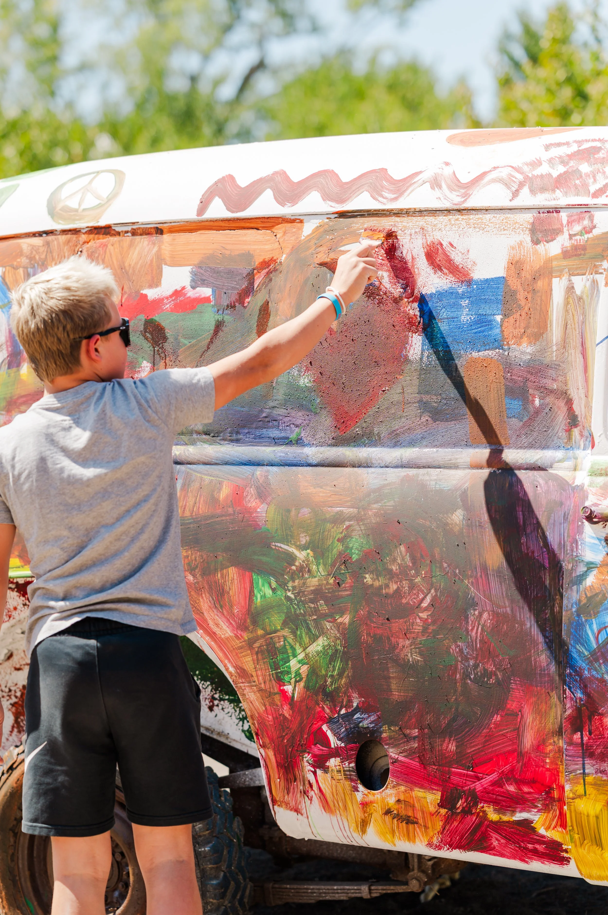 Close-up of a smiling woman with short black hair, wearing a blue top, in a lush green indoor garden.