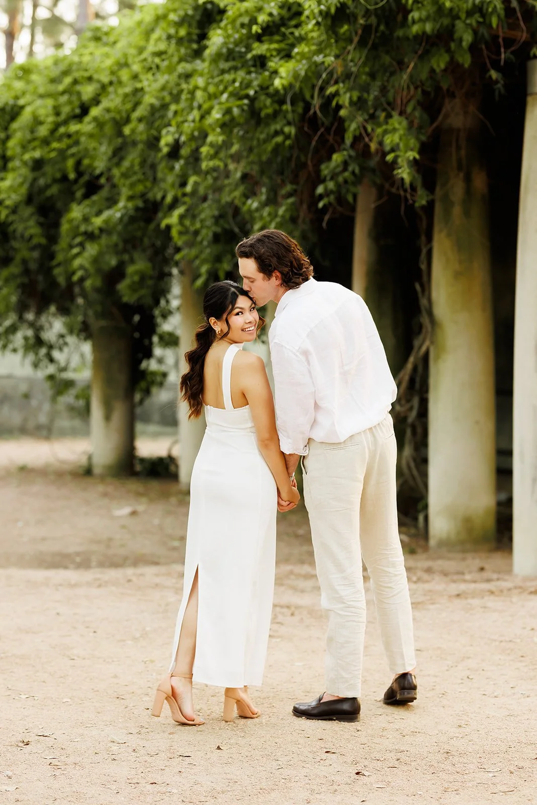 City engagement session on a dirt path in Hermann Park in Houston, TX with a smiling couple holding hands — by Wild Ivy Creative.