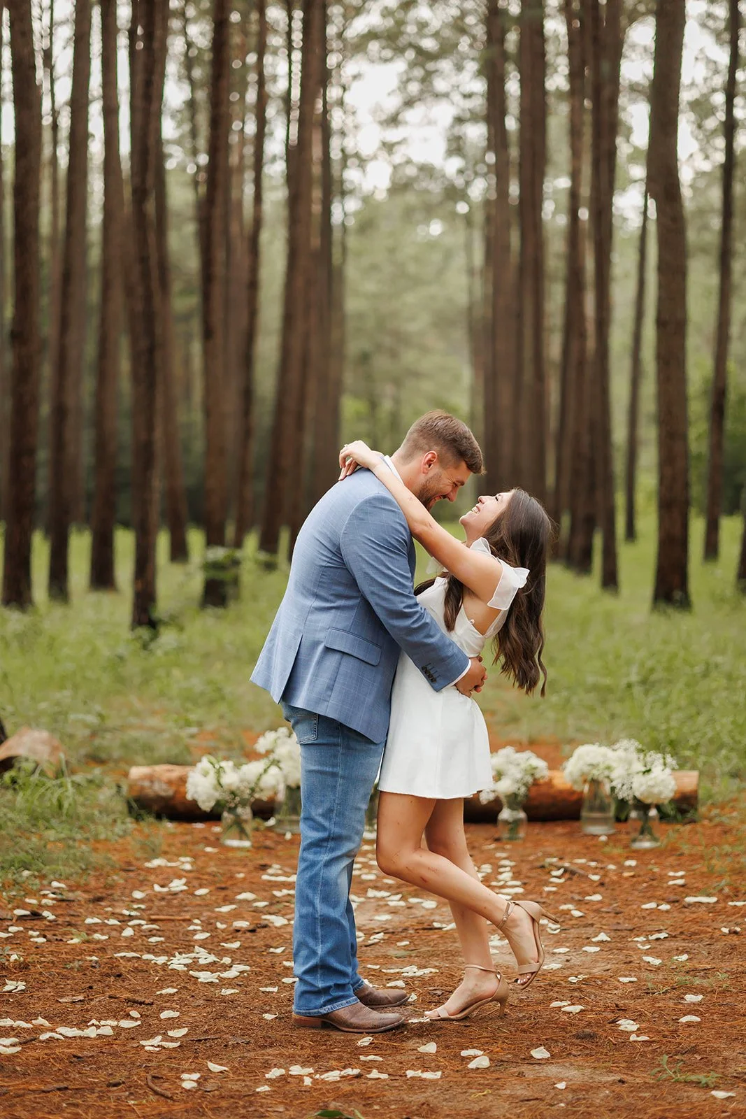 Couple dancing in a forest during a wedding ceremony with flower arrangements and petal decorations