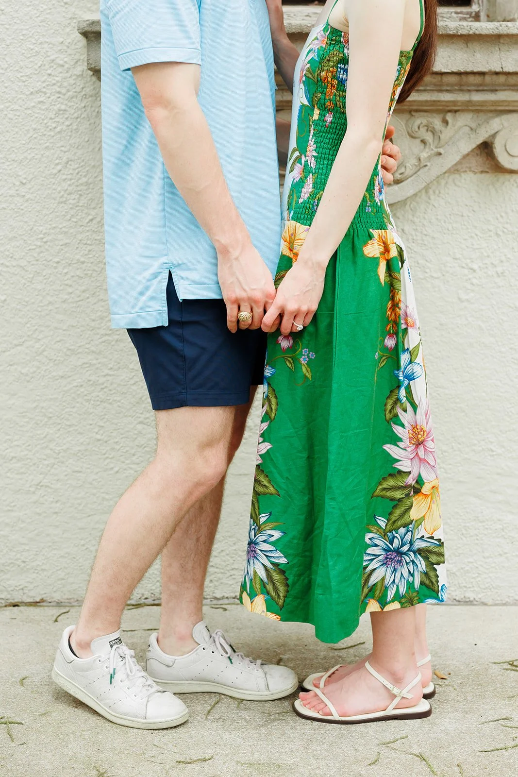 Detail shot of a couple holding hands outdoors during a vibrant summer engagement session in Houston in the Heights.