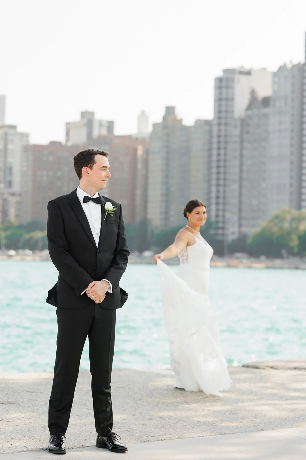 Bride in lace gown and groom in tuxedo standing before city skyline – The Woodlands wedding photographer – Wild Ivy Creative Photography