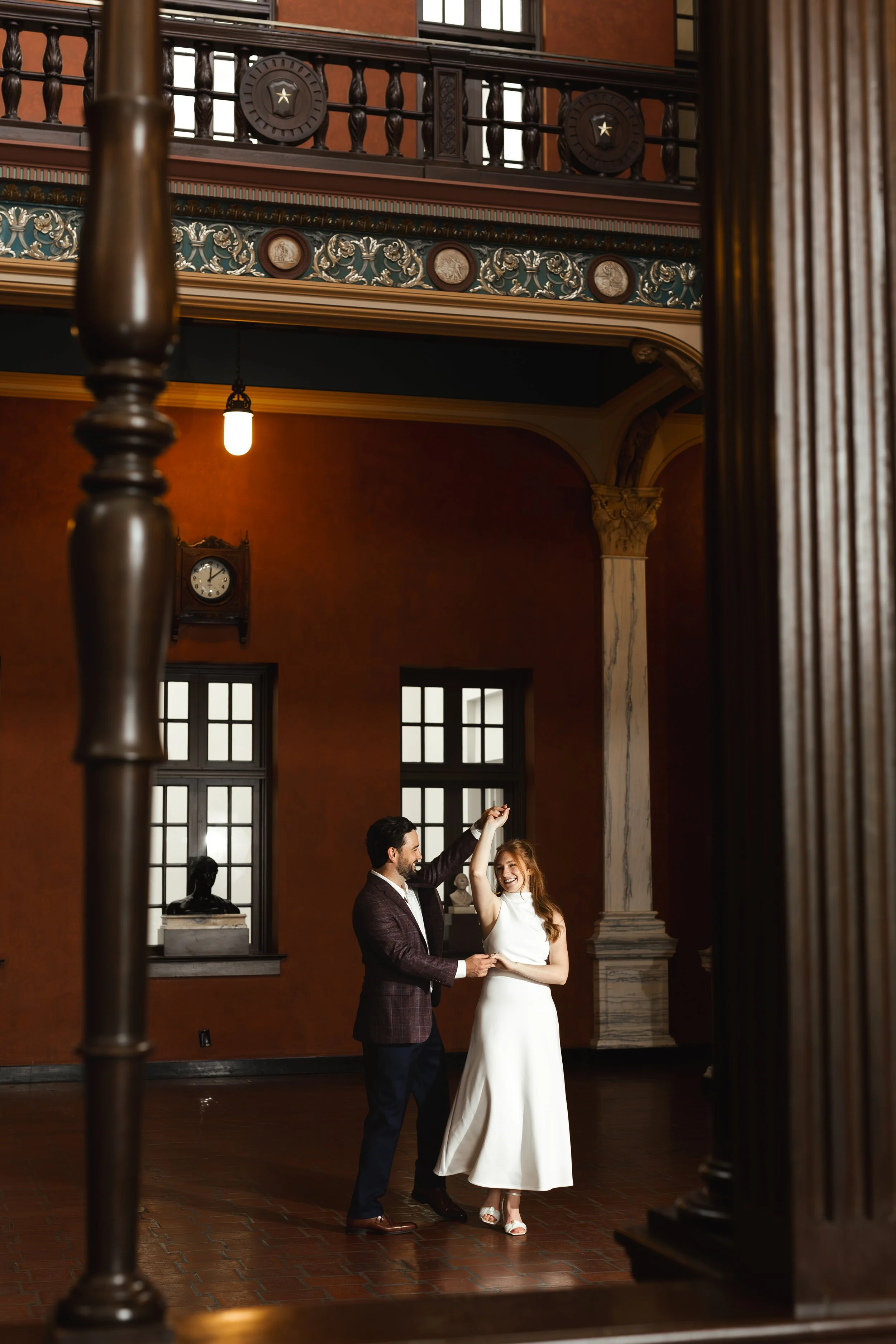 Couple dancing and smiling during an elegant, effortless, and candid editorial style engagement session at the historic Julia Ideson Building in downtown Houston by engagement photographer Wild Ivy Creative Photography