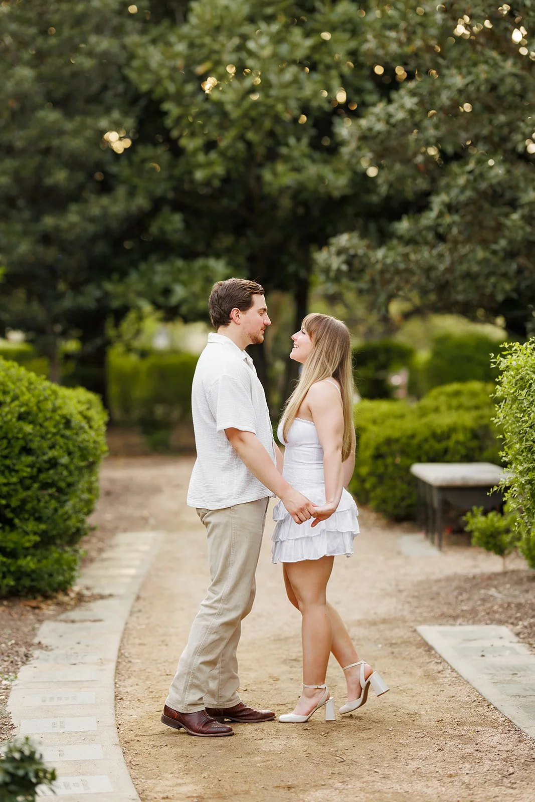 Whimsical garden engagement portrait near downtown Houston, TX — a couple holding hands surrounded by greenery — captured by Wild Ivy Creative.